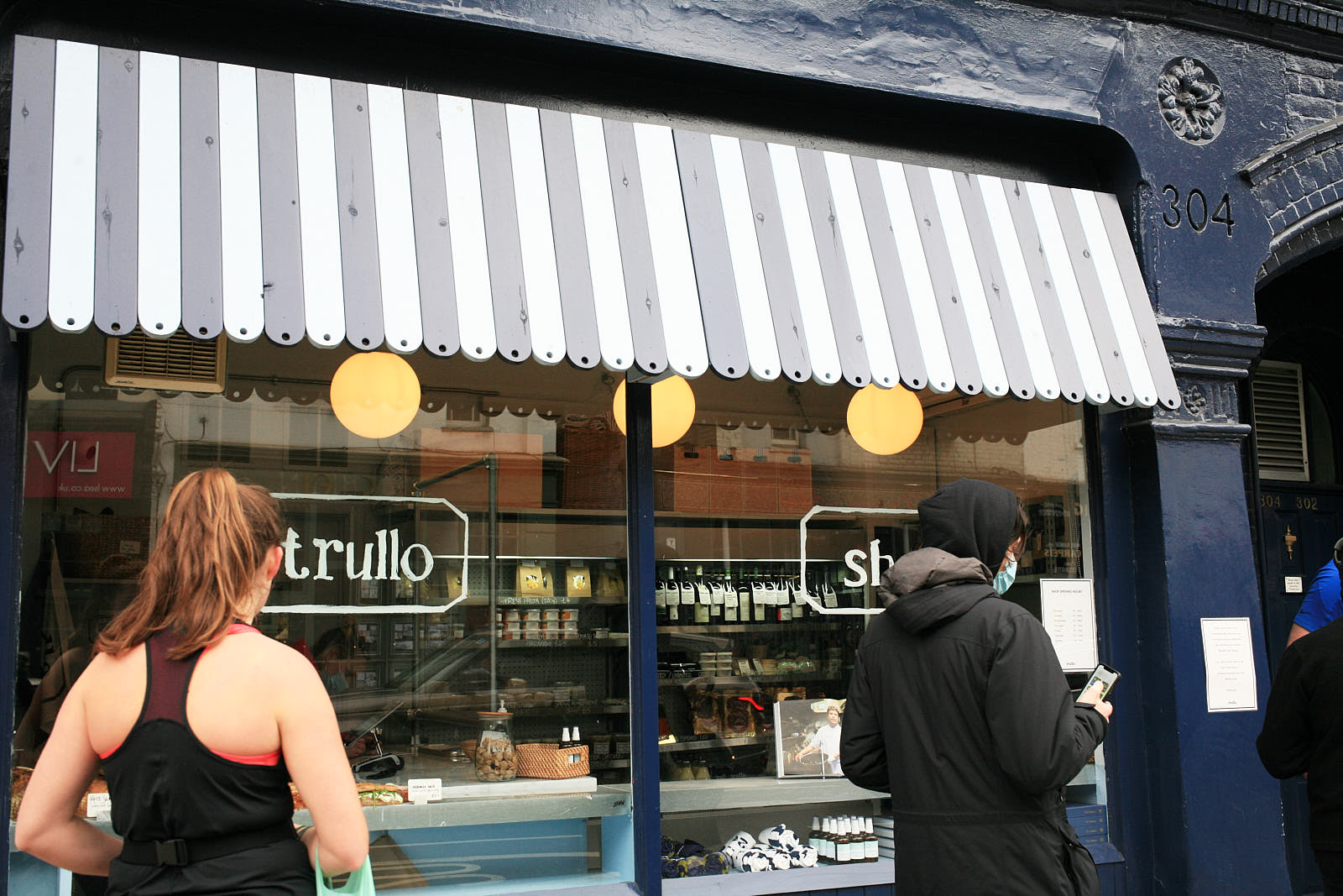 Customers queue outside Trullo, the Italian restaurant in Islington, with a striped awning overhanging the window