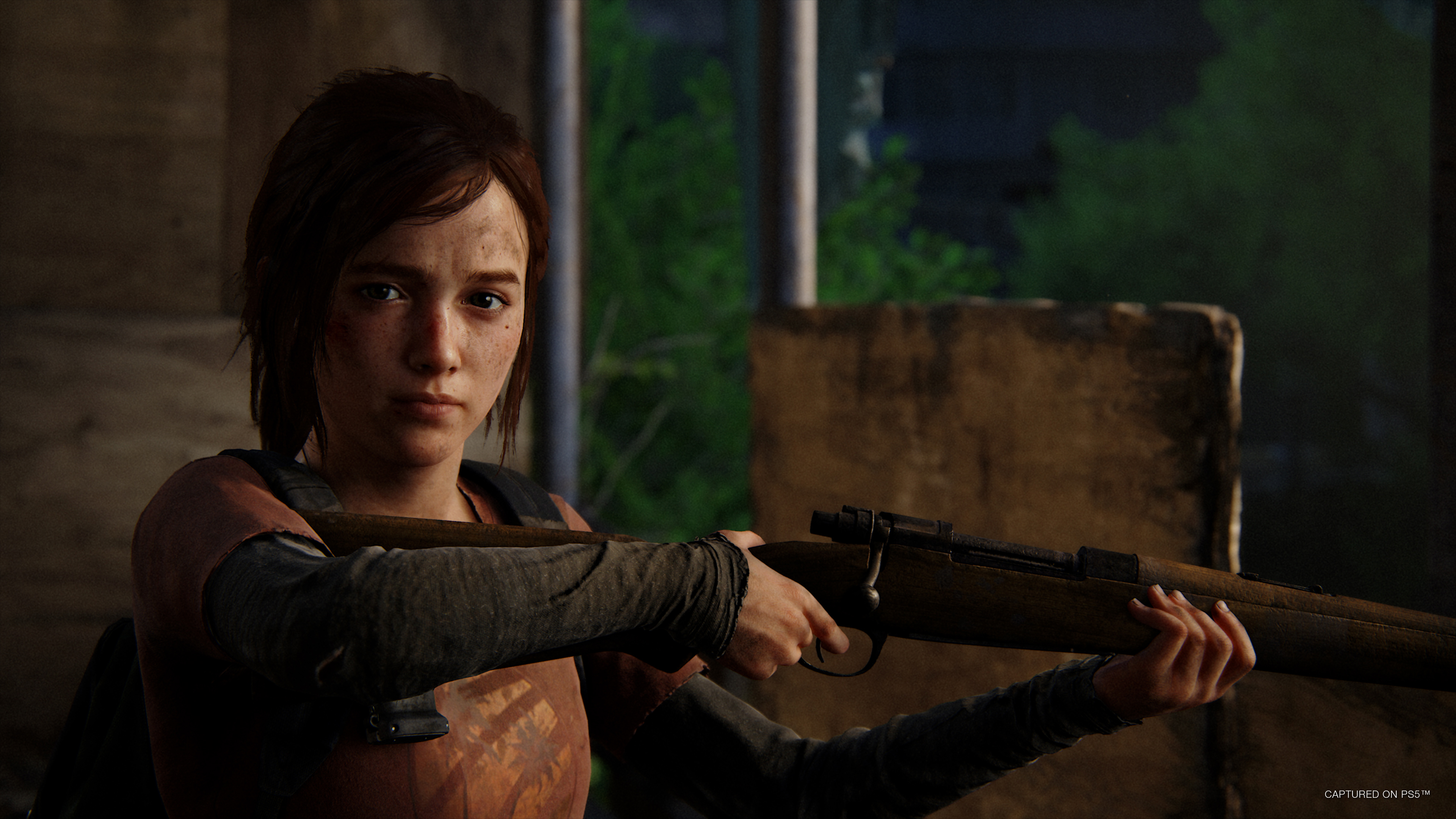 Ellie holds up her rifle in an abandoned building but looks at camera in The Last of Us Part 1 on PS5