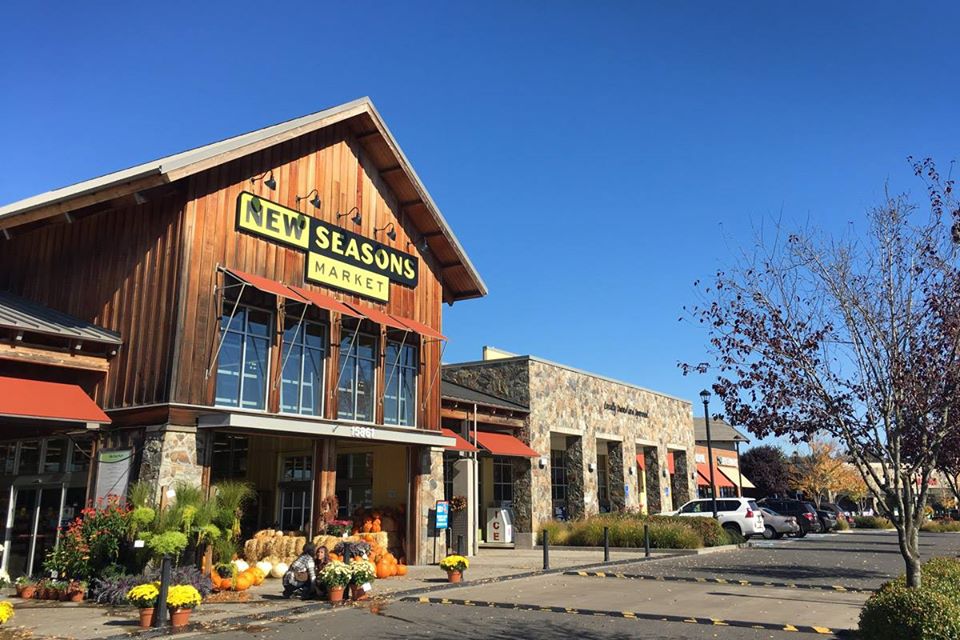 A picture of a New Seasons location with wooden paneling and an autumnal outdoor display.