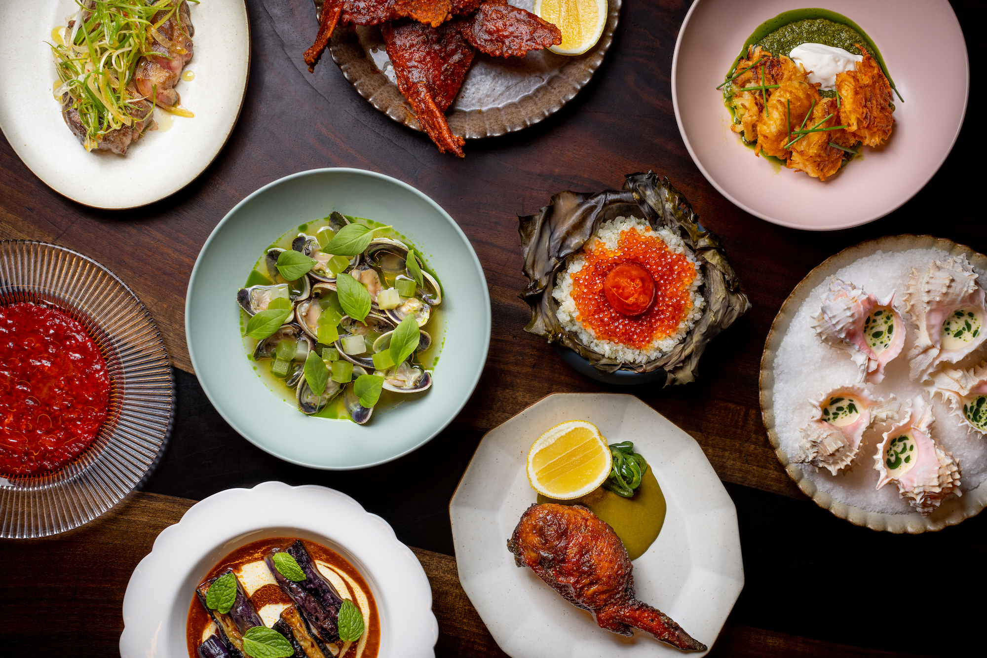 An overhead shot of various bowls and plates filled with seafood fresh off a grill.