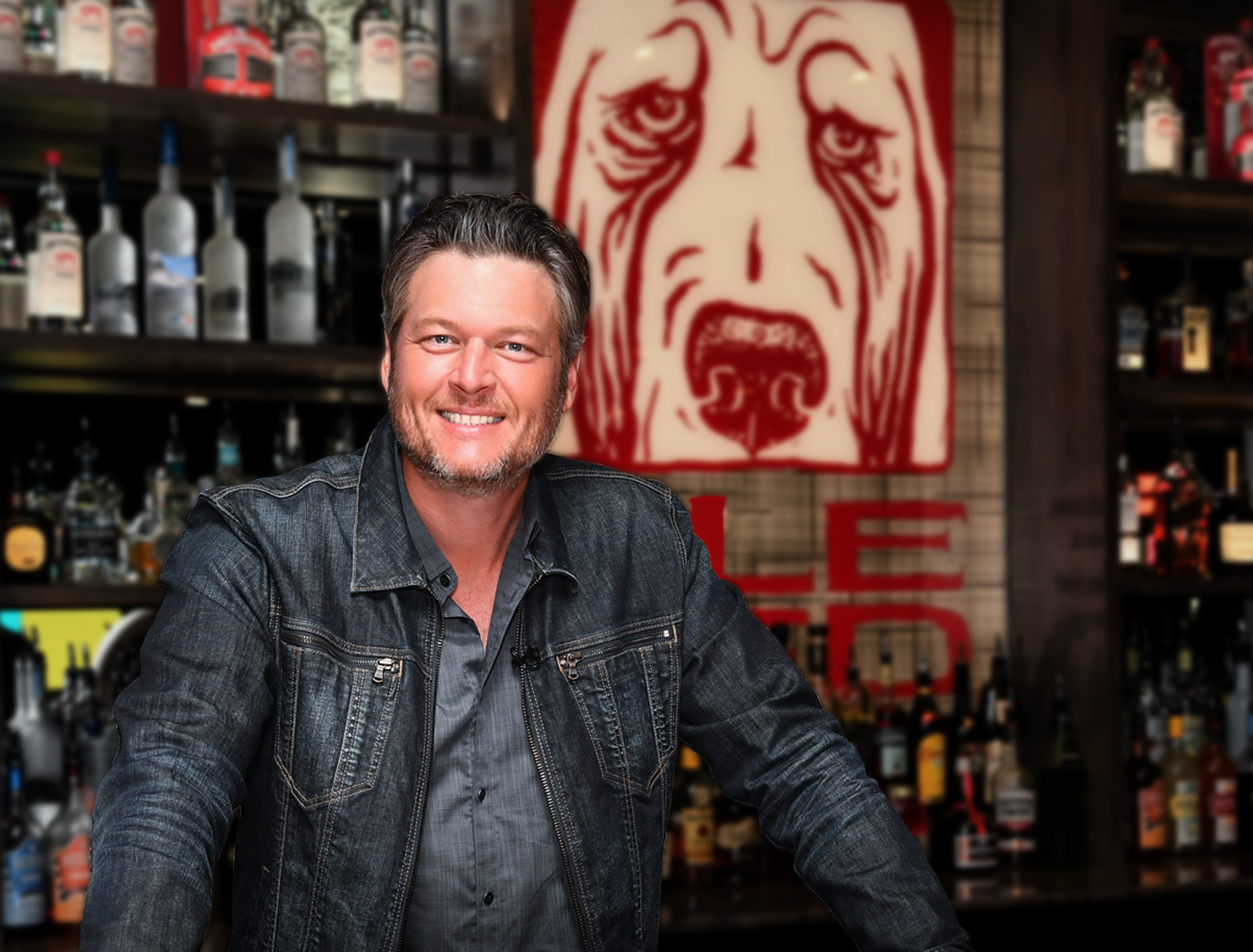 Blake Shelton poses in front of a poster for Ole red