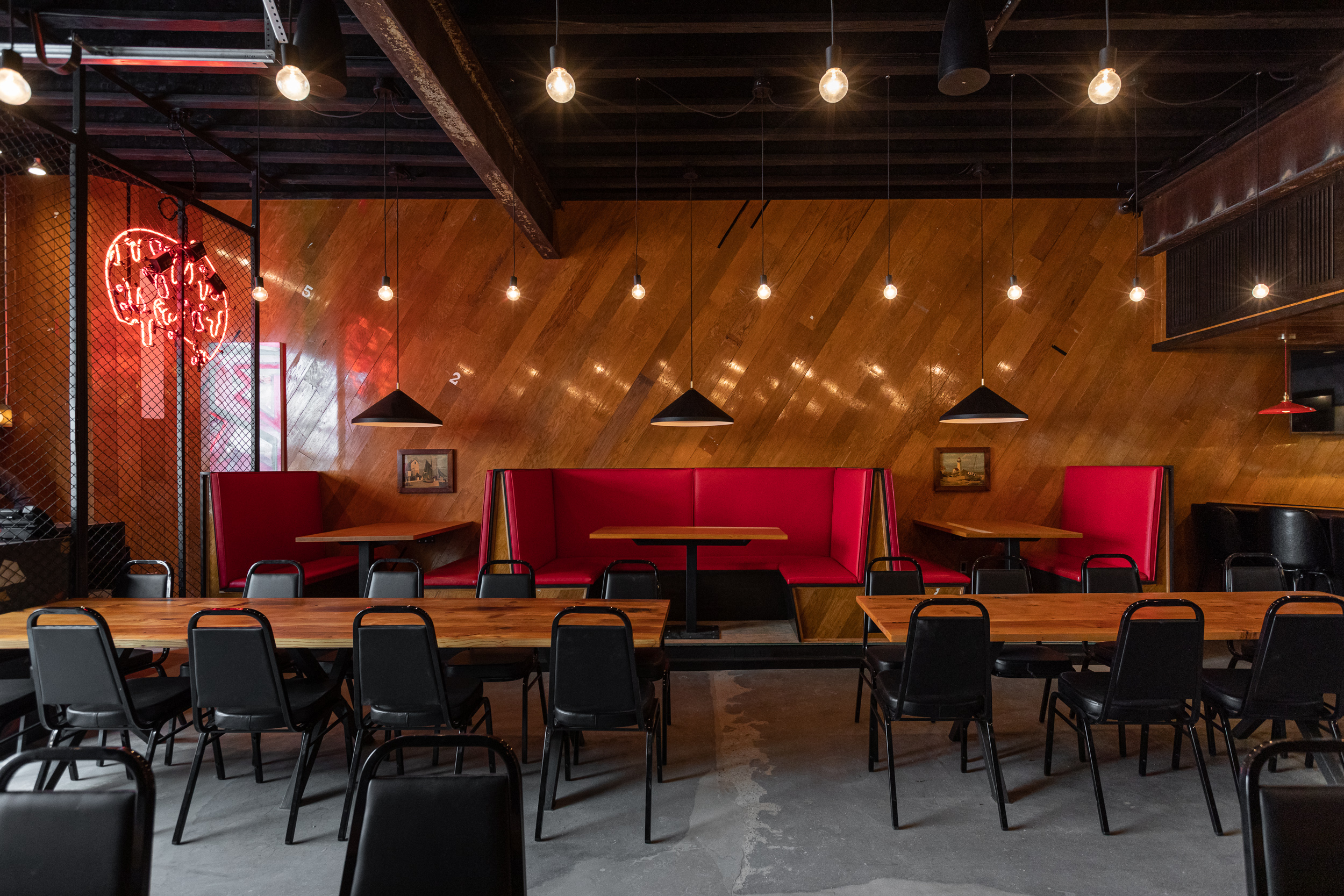 Wood paneled walls are lined with red booths, with long wood tables surrounded by eight chairs each at the center of the dining room.