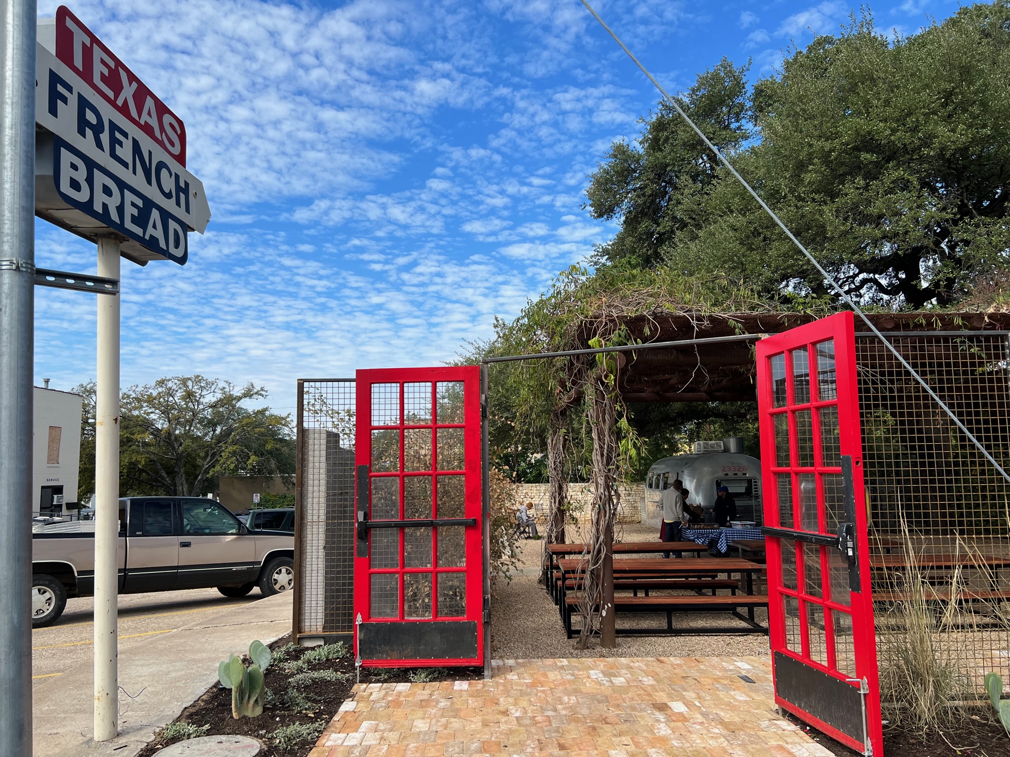 A patio with open red gate doors next to a sign that reads “Texas French Bread.”
