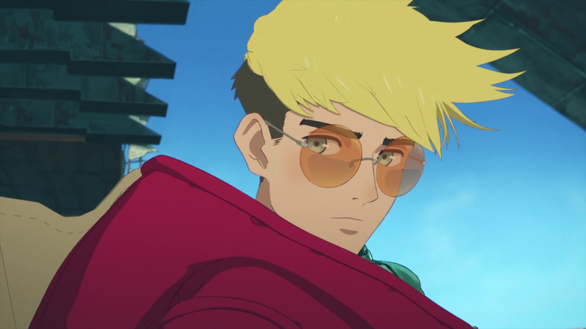 A blond anime boy with round tinted glasses looks solemnly at the viewer.
