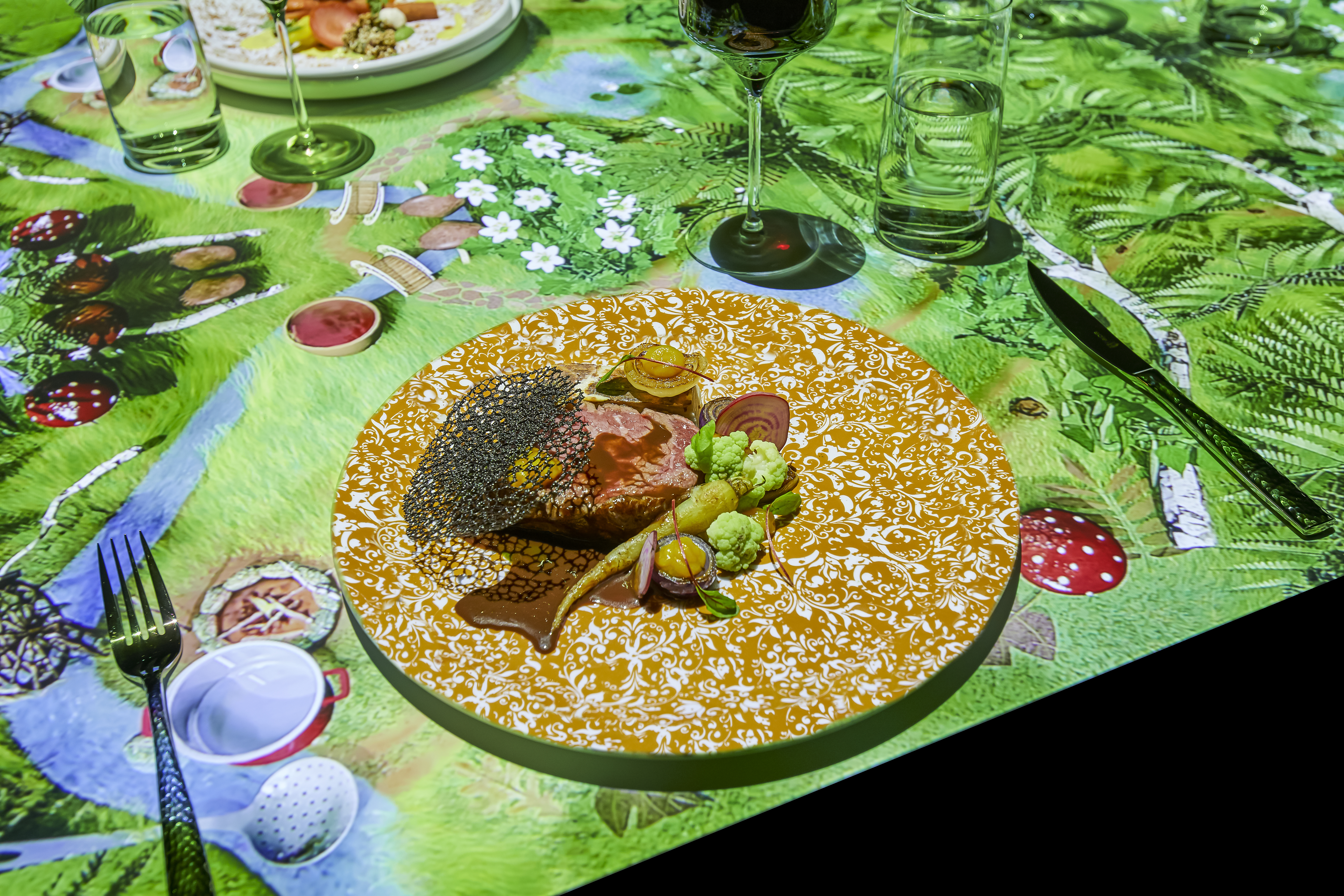 A table with a round plate full of food and colorful computer graphics.