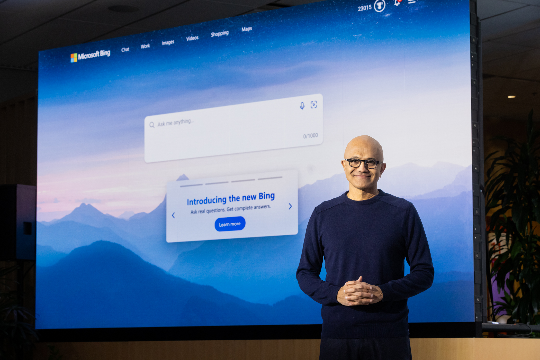 Microsoft chair and CEO Satya Nadella standing in front of a wall-sized screen displaying the new Bing search engine.
