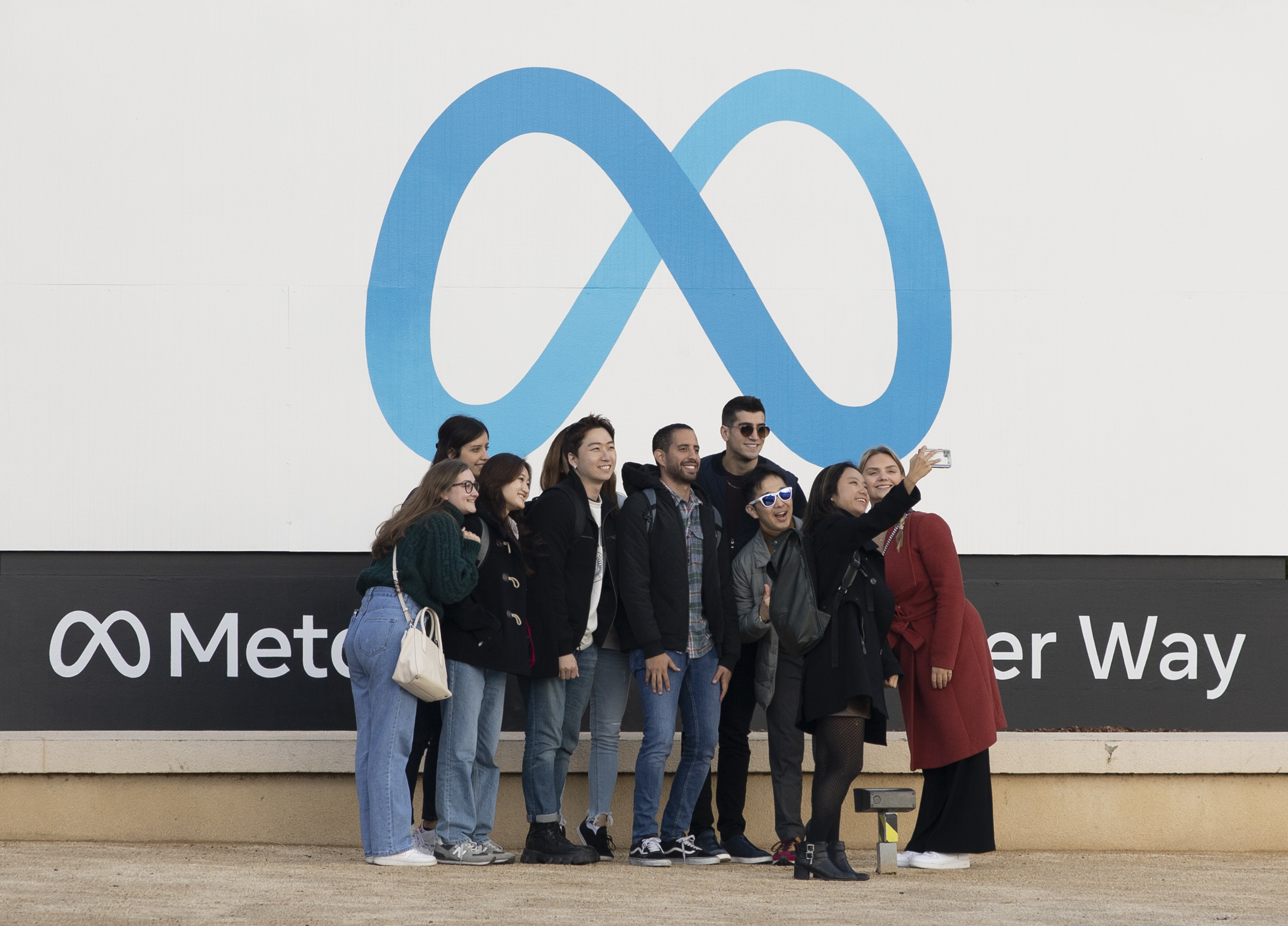 A group of people standing below the Meta infinity symbol.