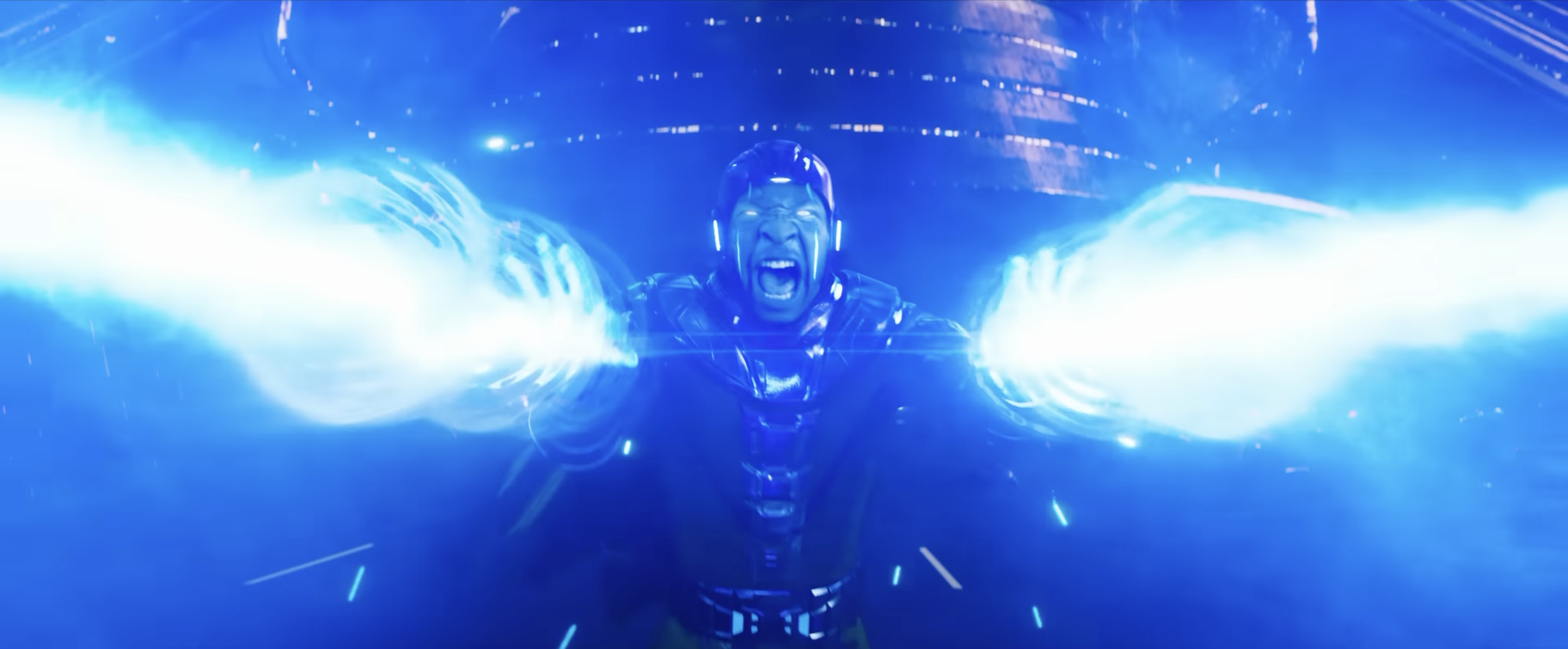 Kang (Jonathan Majors) roars and fires beams of blue energy from his hands. The energy tinges his face the same color as his comics inspiration, and makes the vertical seams on his face glow, in Ant-Man &amp; the Wasp: Quantumania.