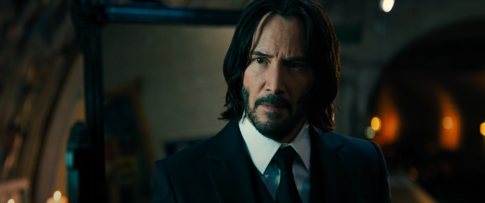 Keanu Reeves as John Wick in a suit looking toward the camera