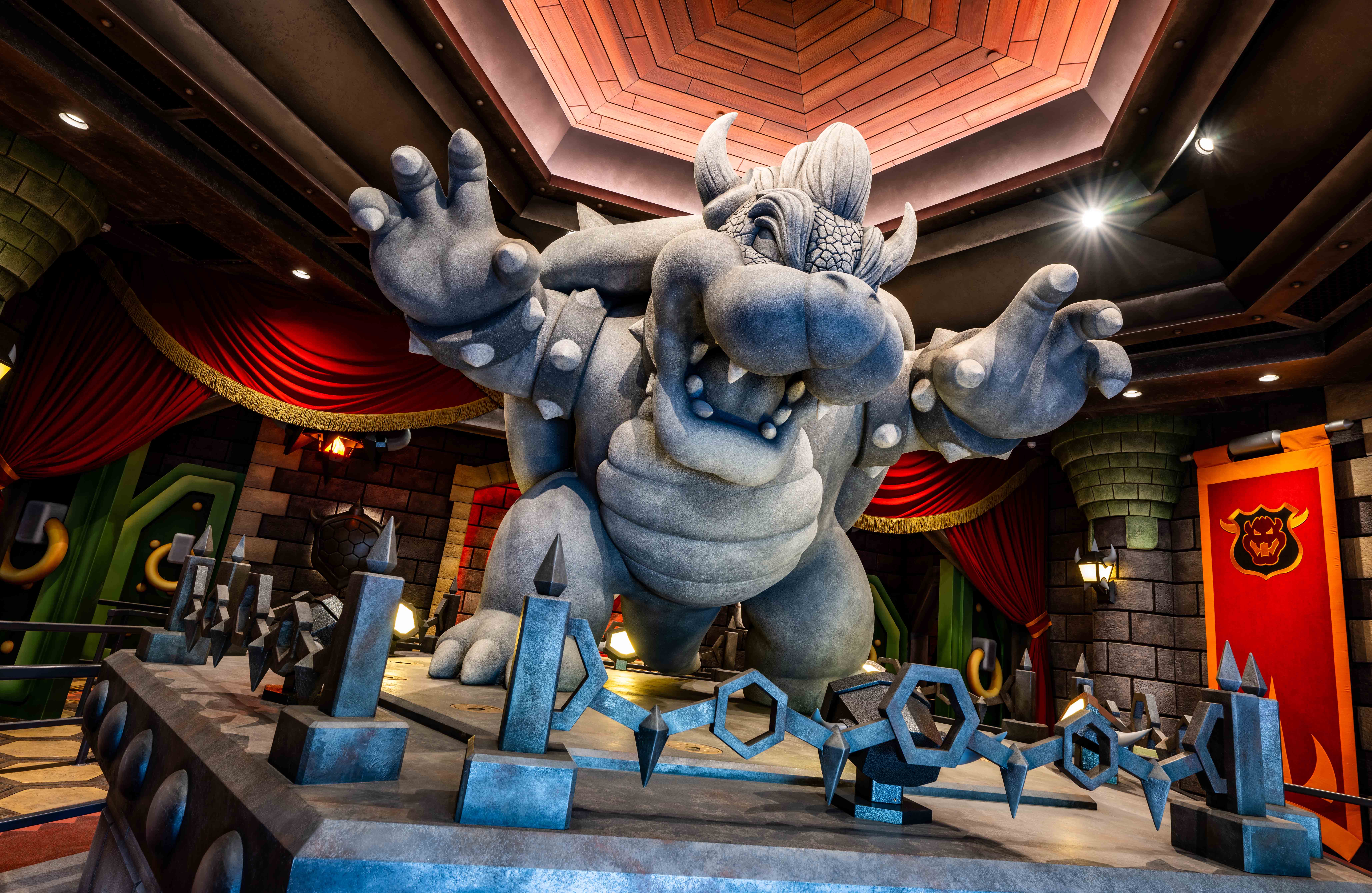 A statue of Bowser in front of his castle in the queue for Super Nintendo World’s attraction Mario Kart: Bowser’s Challenge.