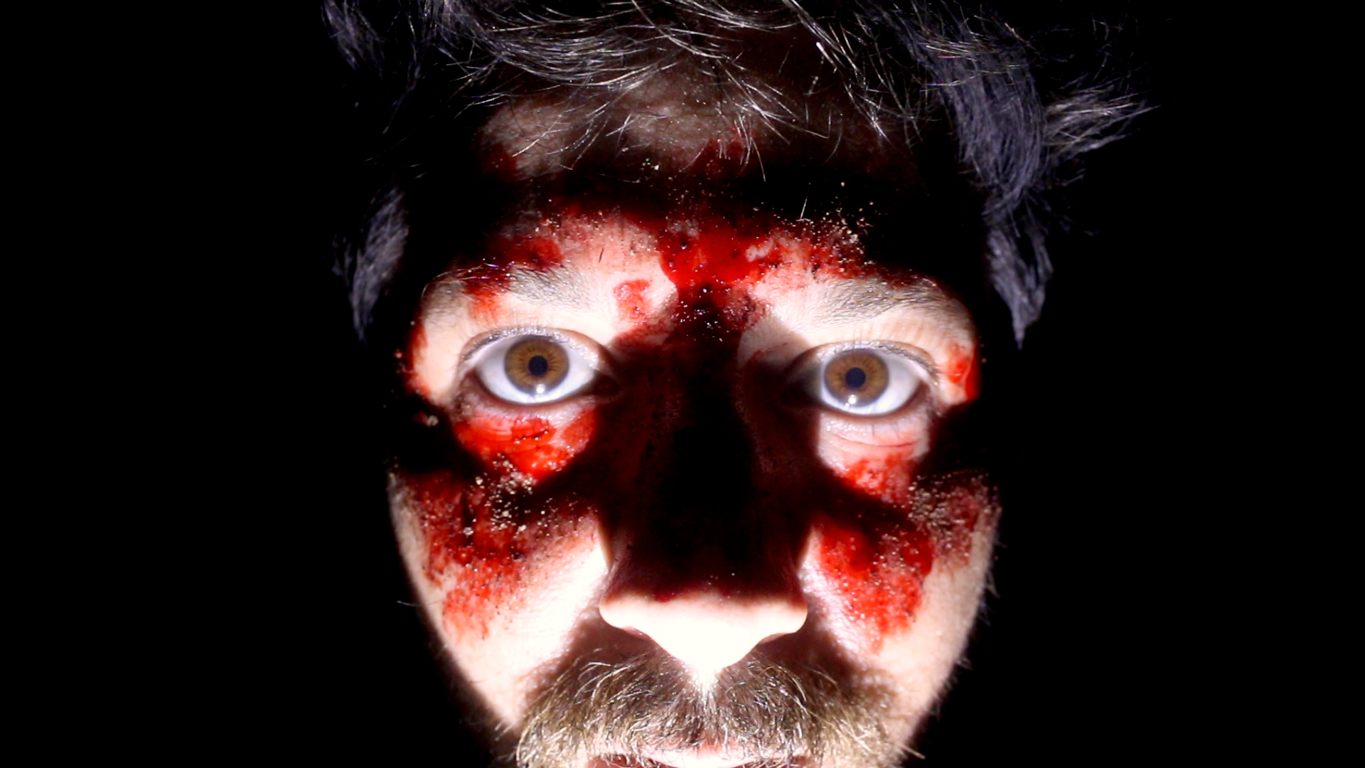 Robbie Banfitch stares at the camera with blood on his face in The Outwaters