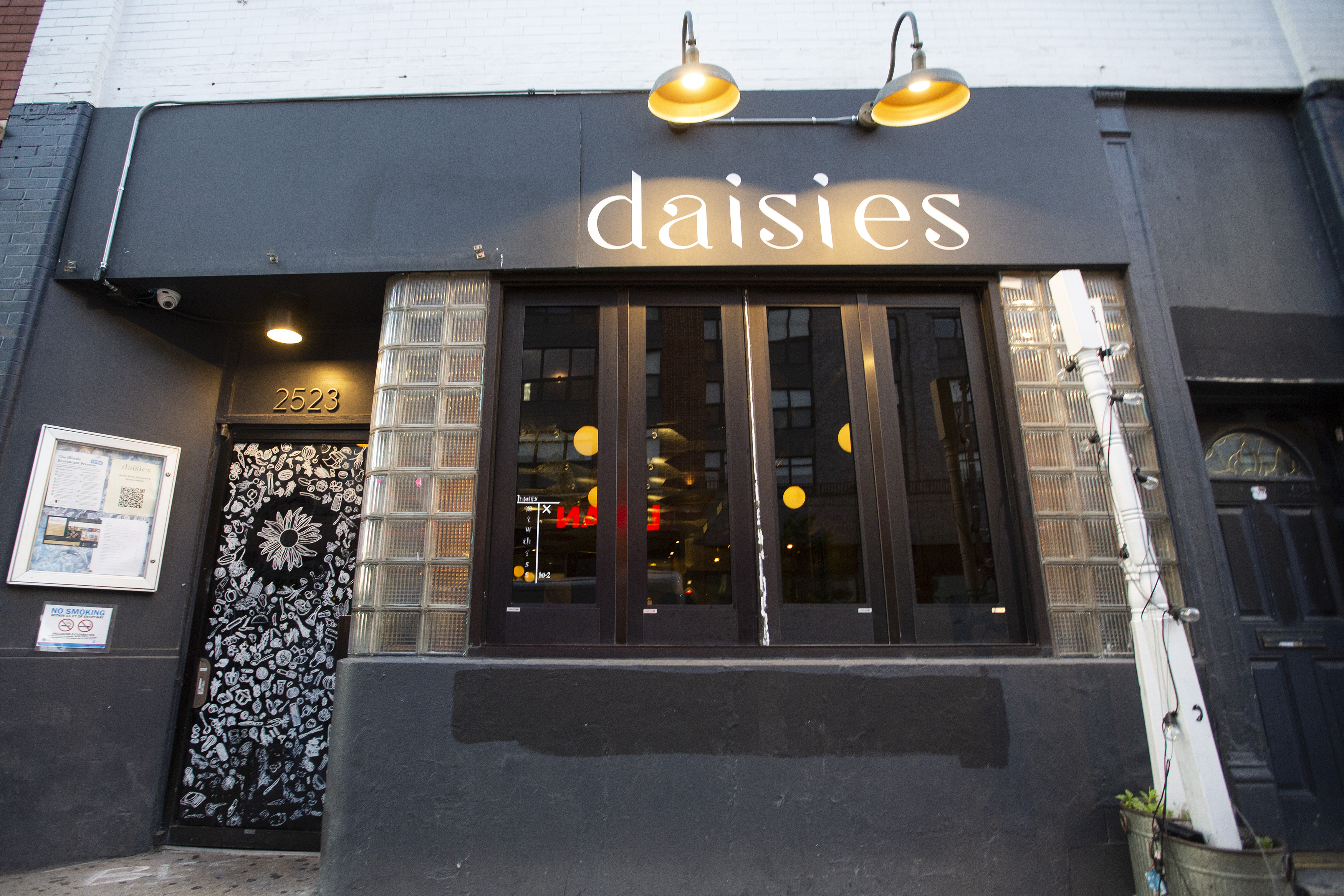 A storefront restaurant with a sign that reads “Daisies.”