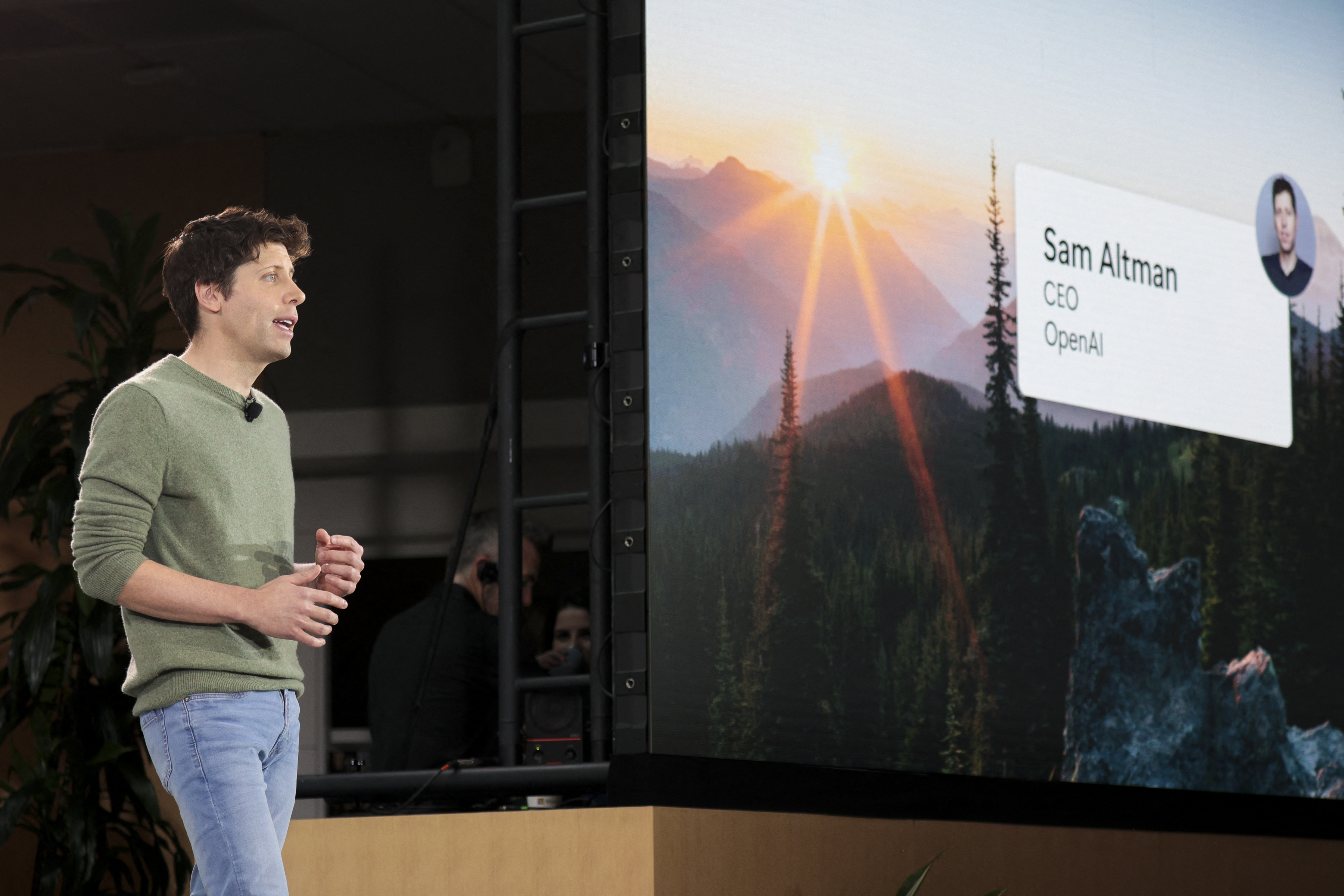 Sam Altman onstage with a projector screen seen to the right. 