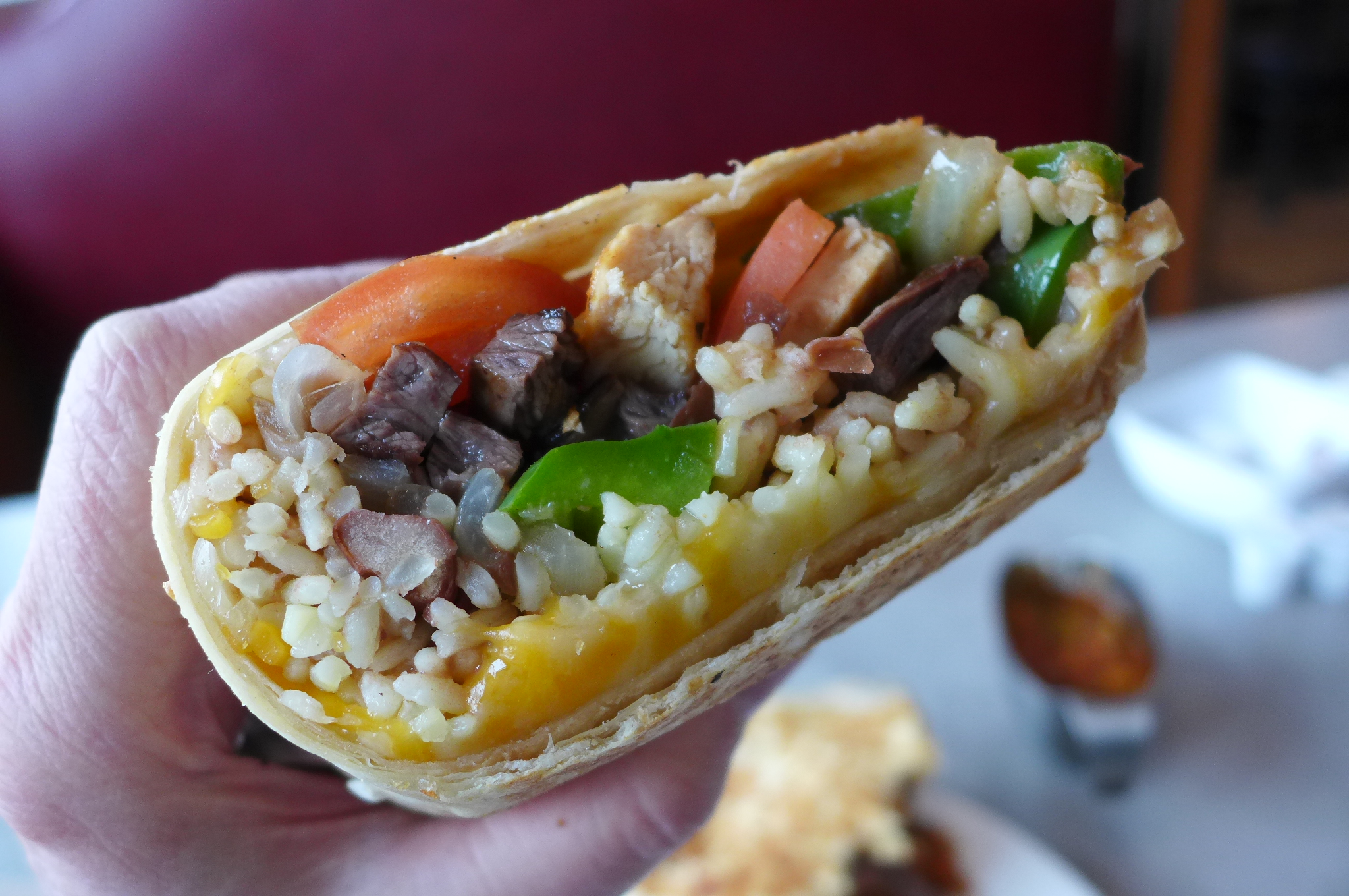 A burrito seen in cross section being held up by a hand.
