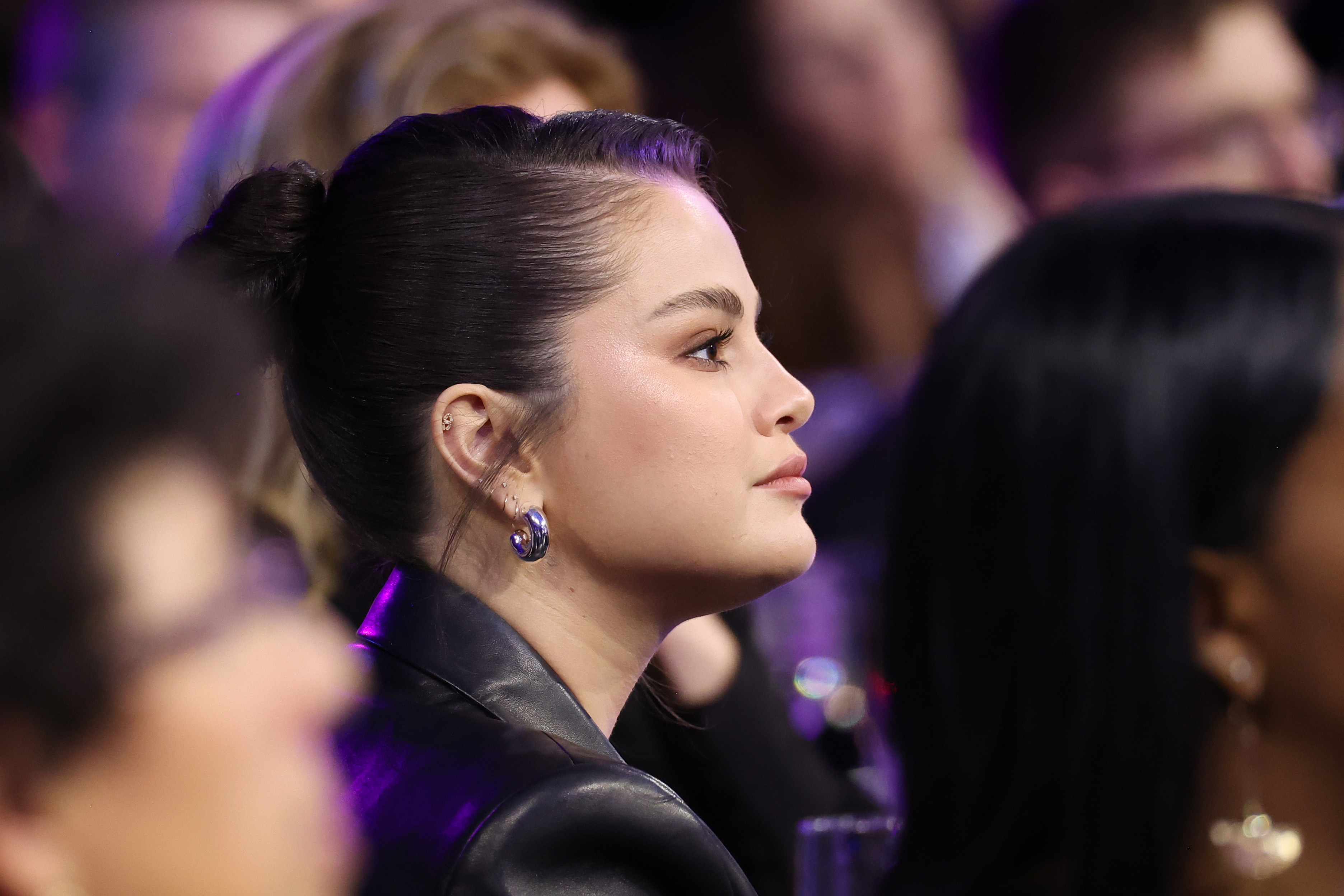 Selena Gomez, in profile, sitting in an audience.