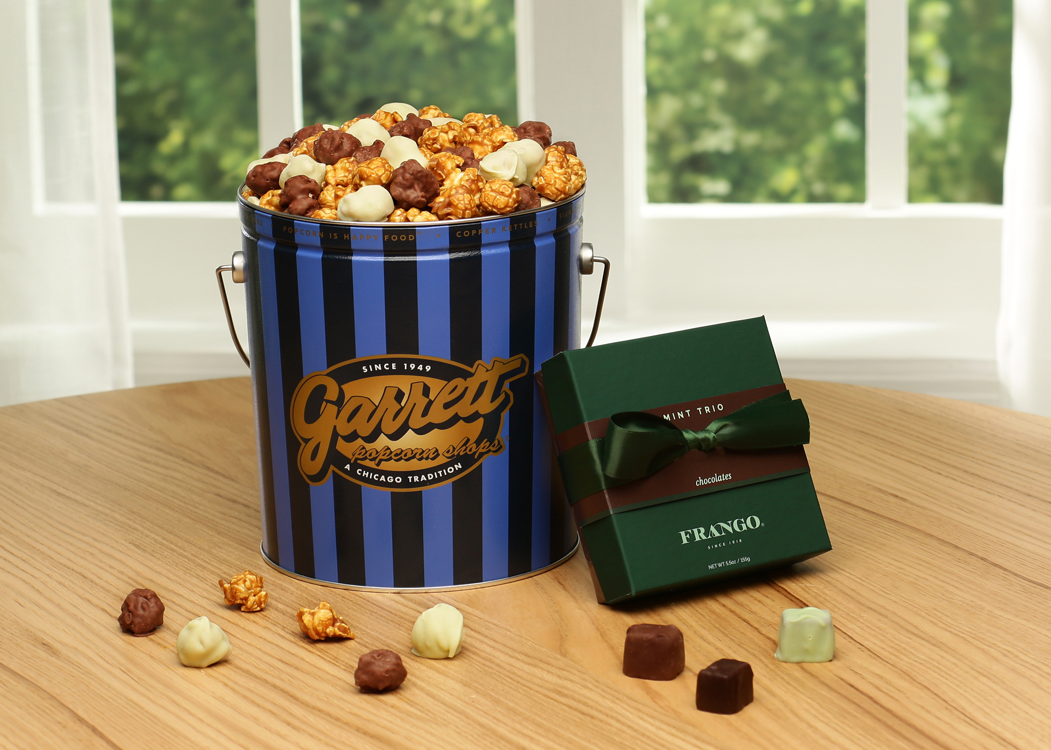 A tin of popcorn next to a box of green chocolates.