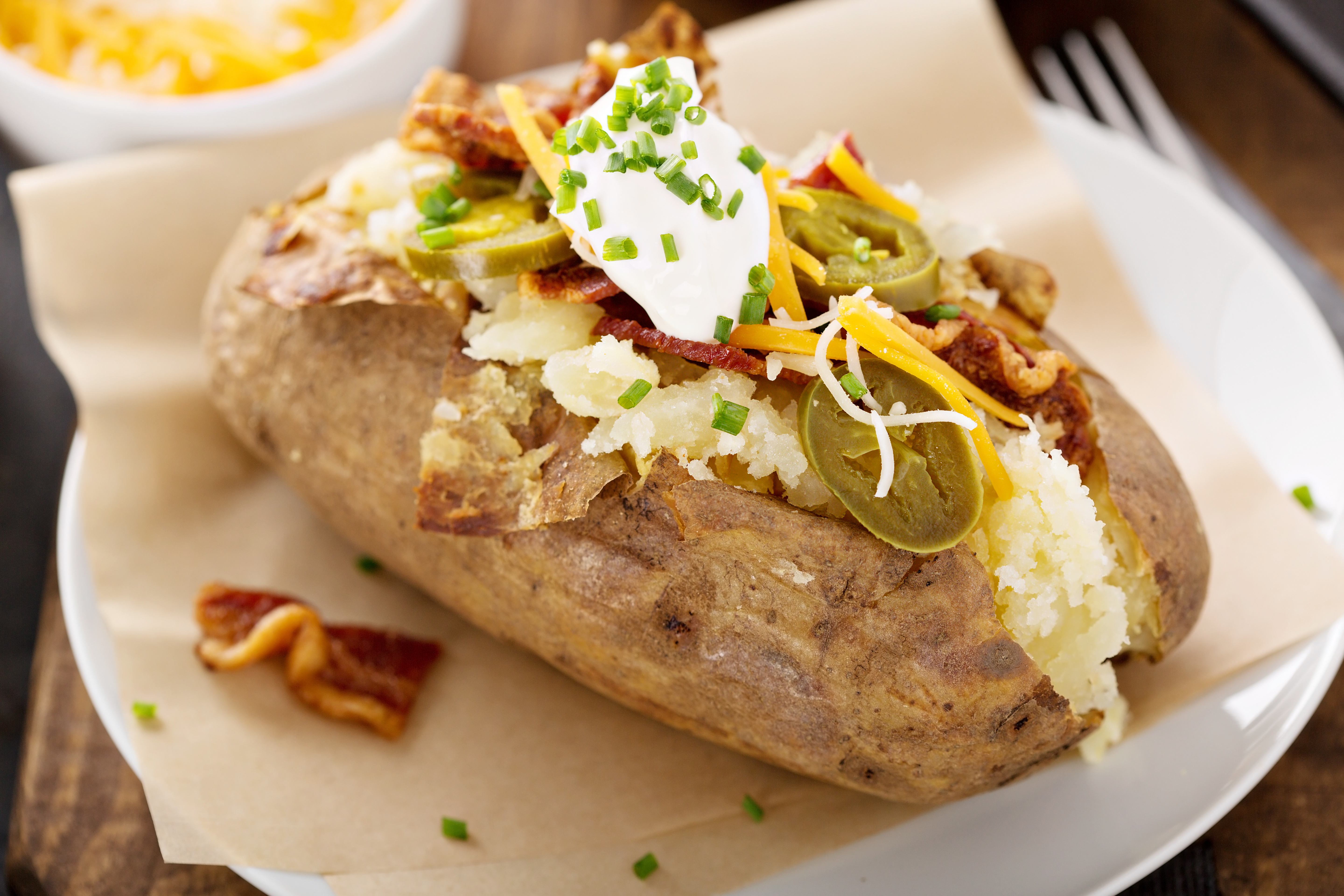 A baked potato topped with bacon, cheddar, sour cream, and jalepenos 