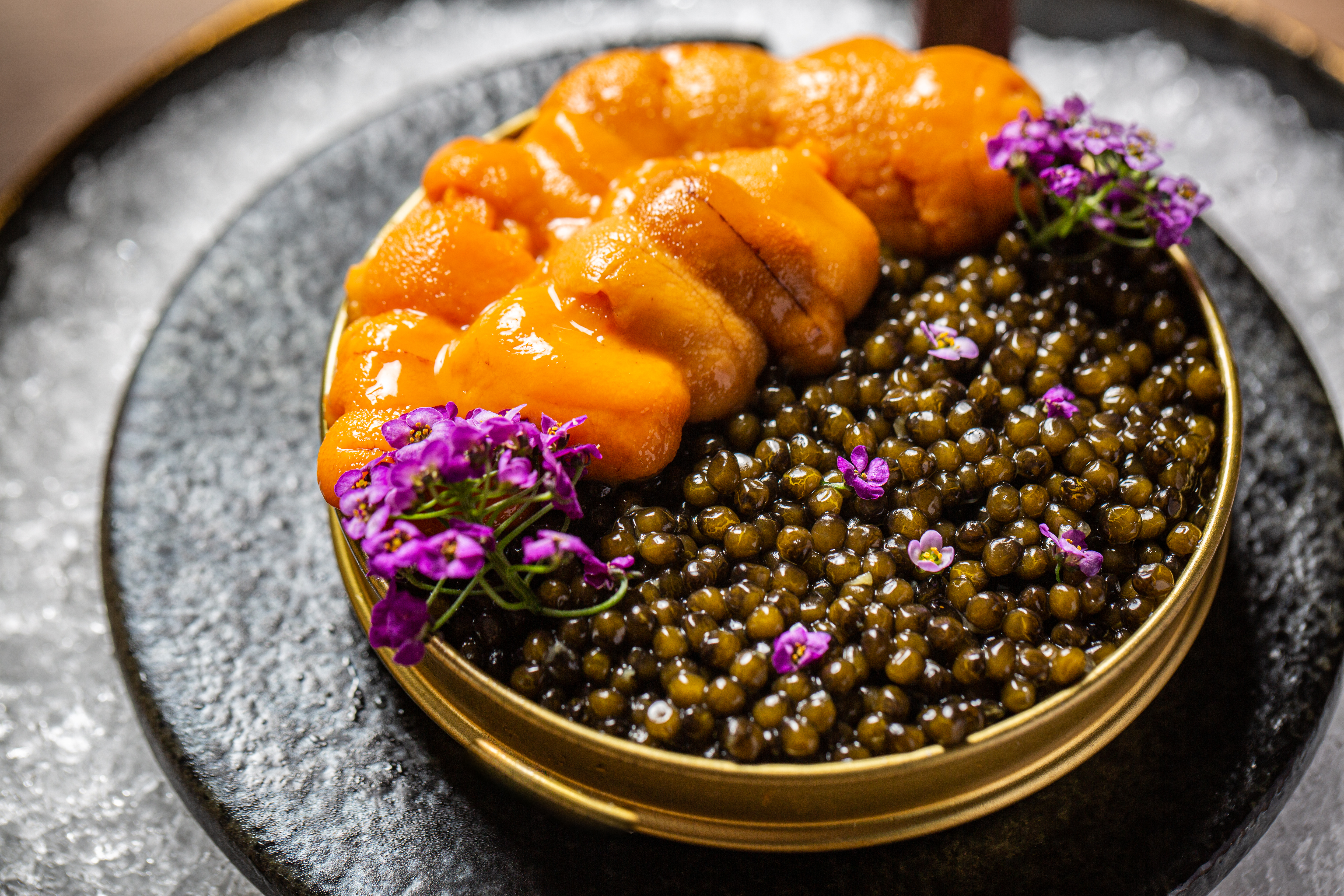 A close up shot of a tin of caviar with uni on top.
