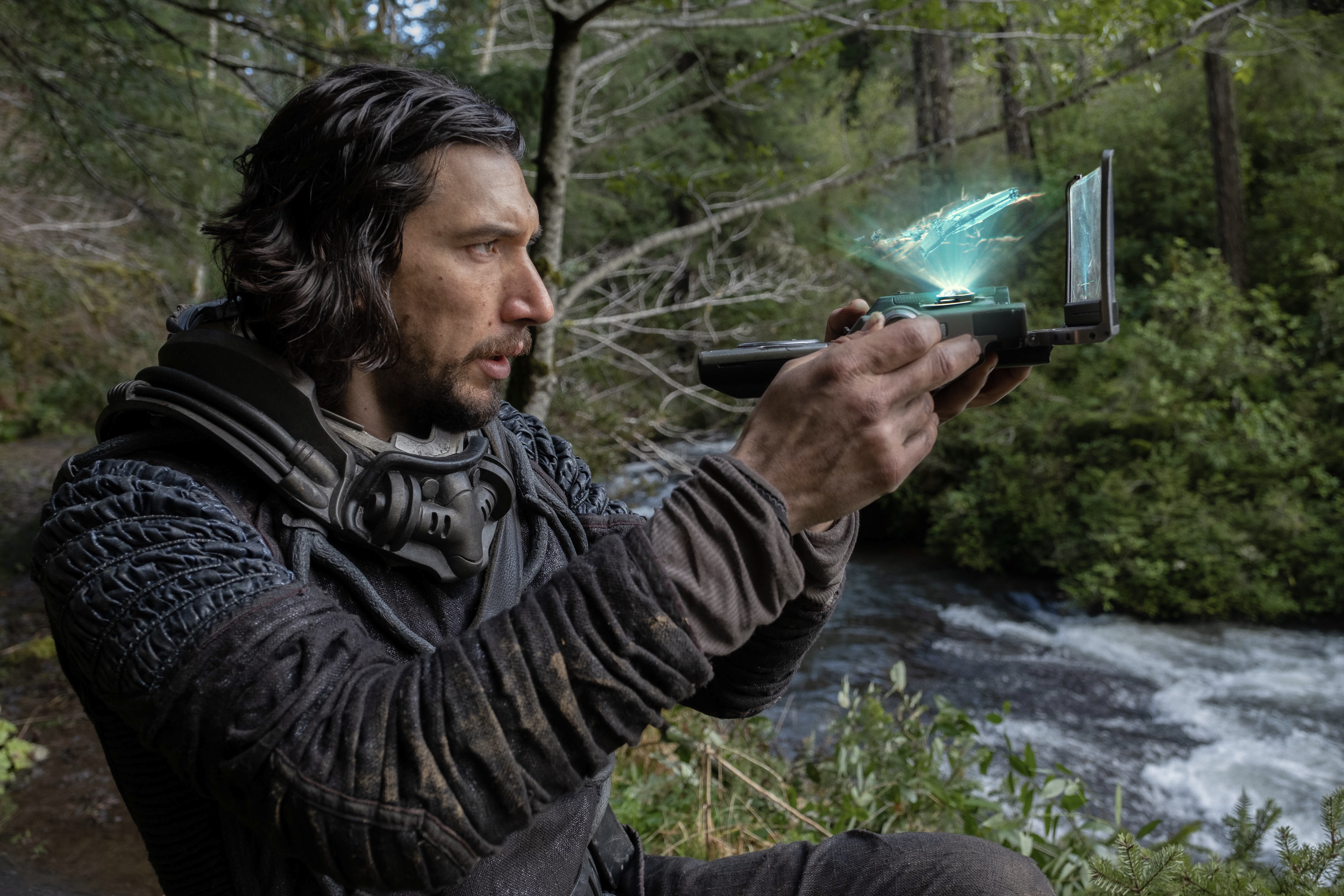 Adam Driver’s Mills holds up a 3D hologram of his ship while he navigates the prehistoric jungles of Earth in 65