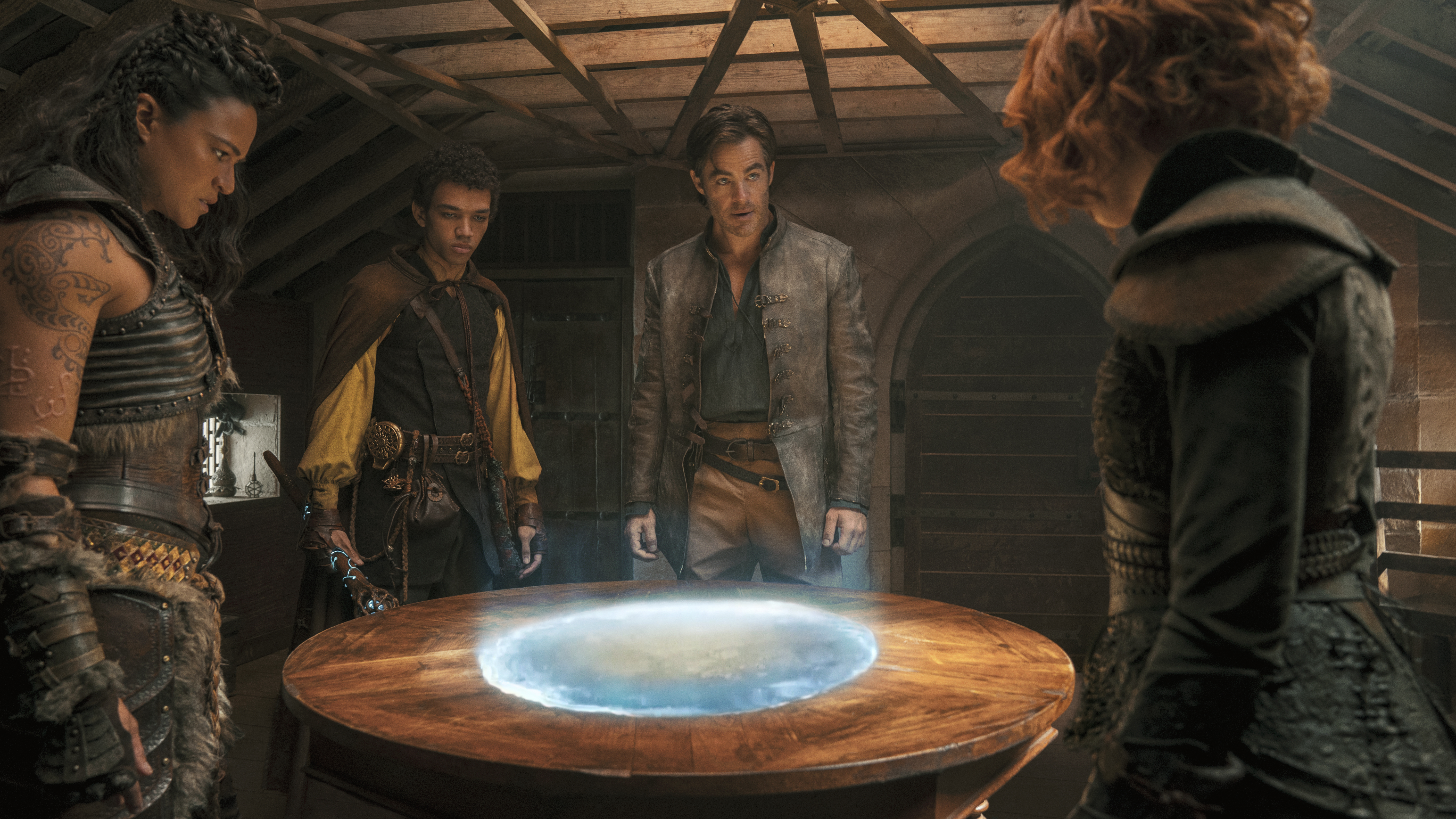 A grubby, battered D&amp;D party (Michelle Rodriguez, Justice Smith, Chris Pine, and Sophia Lillis) gather around a glowing circular map in a scene from Dungeons &amp; Dragons: Honor Among Thieves