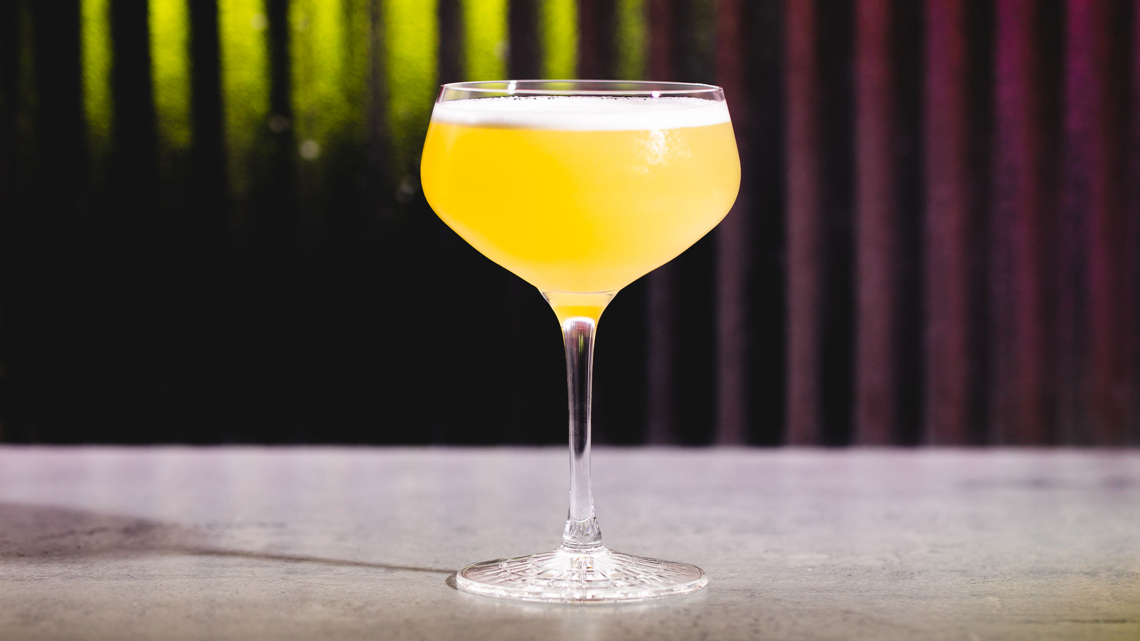 A yellow cocktail in a cocktail coupe