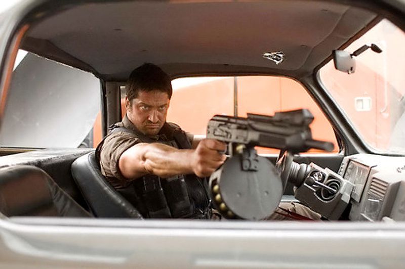 Gerard Butler holds a comically large gun while driving a car in Gamer.