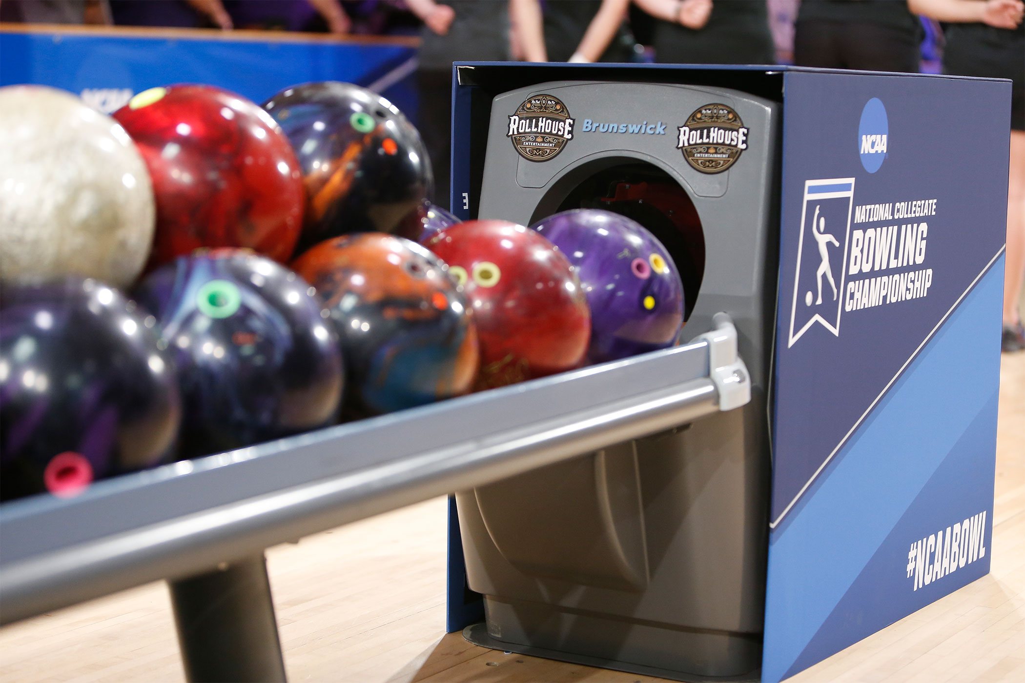 Bowling balls rest on the return rack, which is wrapped in an NCAA Bowling Championship cover.