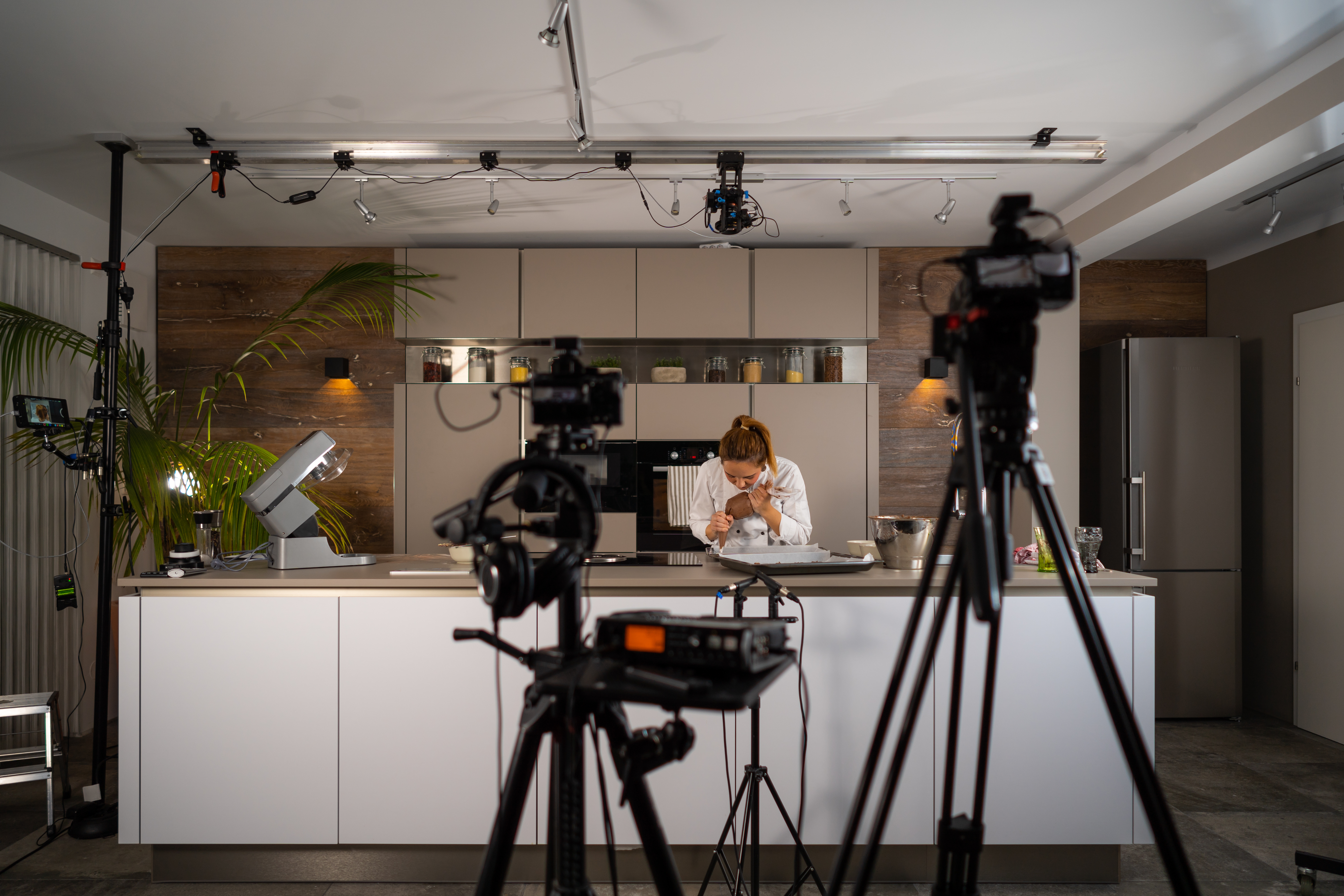 a woman works in a kitchen surrounded by cameras 