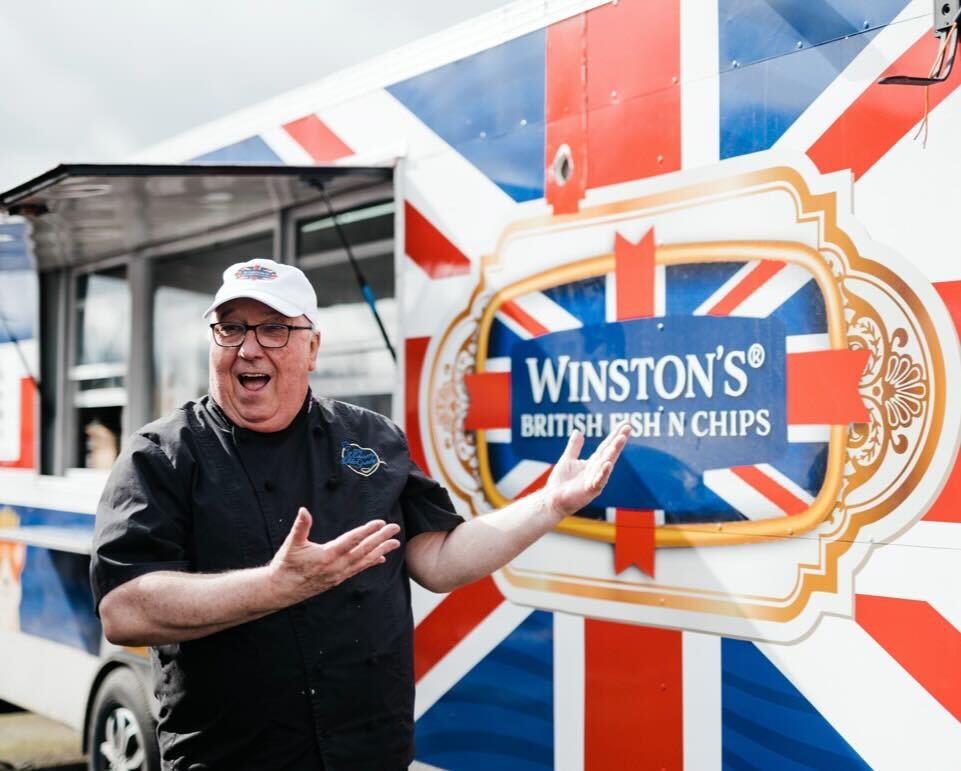 Chef Darren McGrady stands in front of his food cart, which is decorated with a Union Jack.