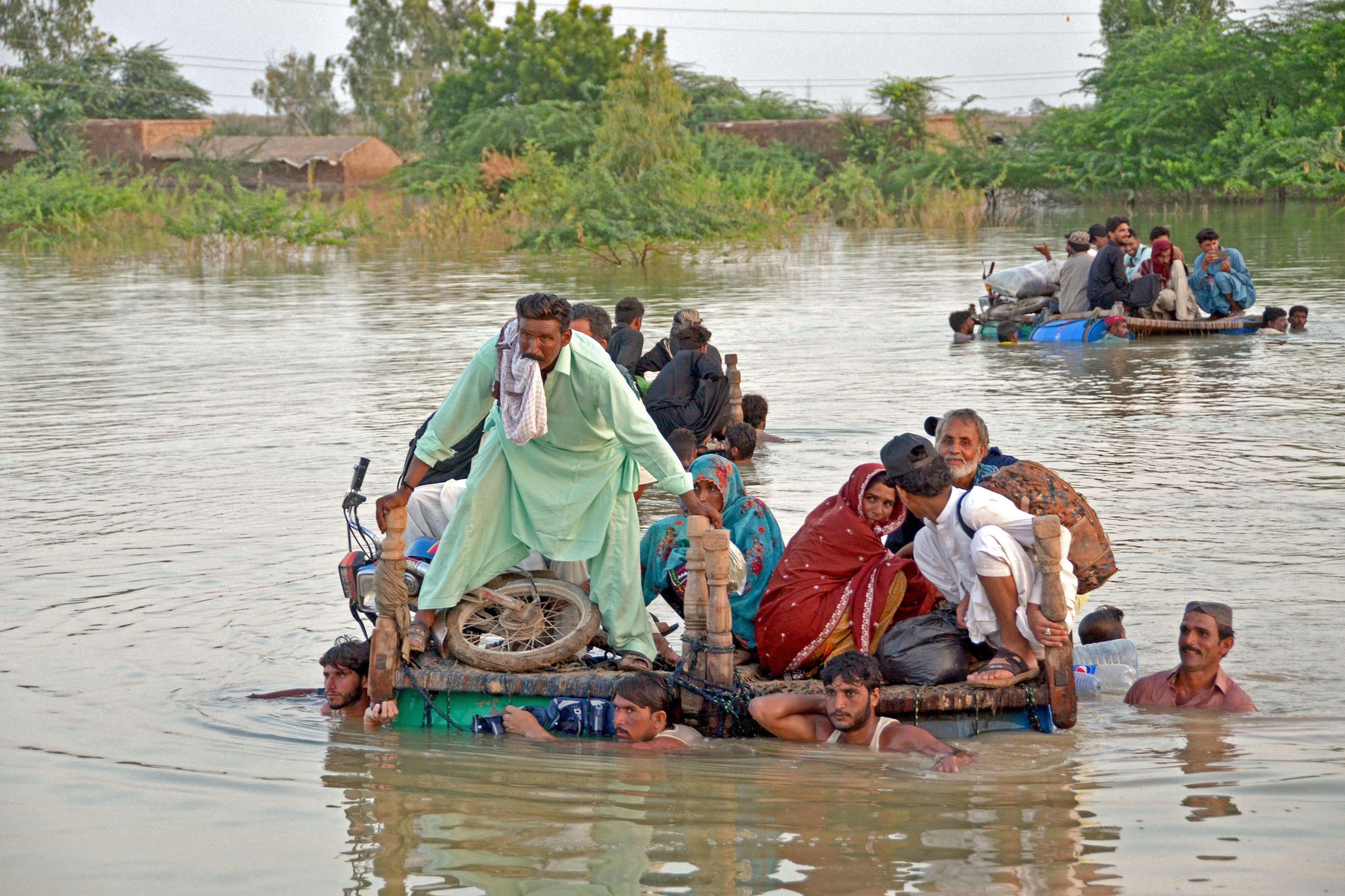 Internally displaced people wade through floodwaters after heavy monsoon rains in Pakistan’s Balochistan province on September 8, 2022.