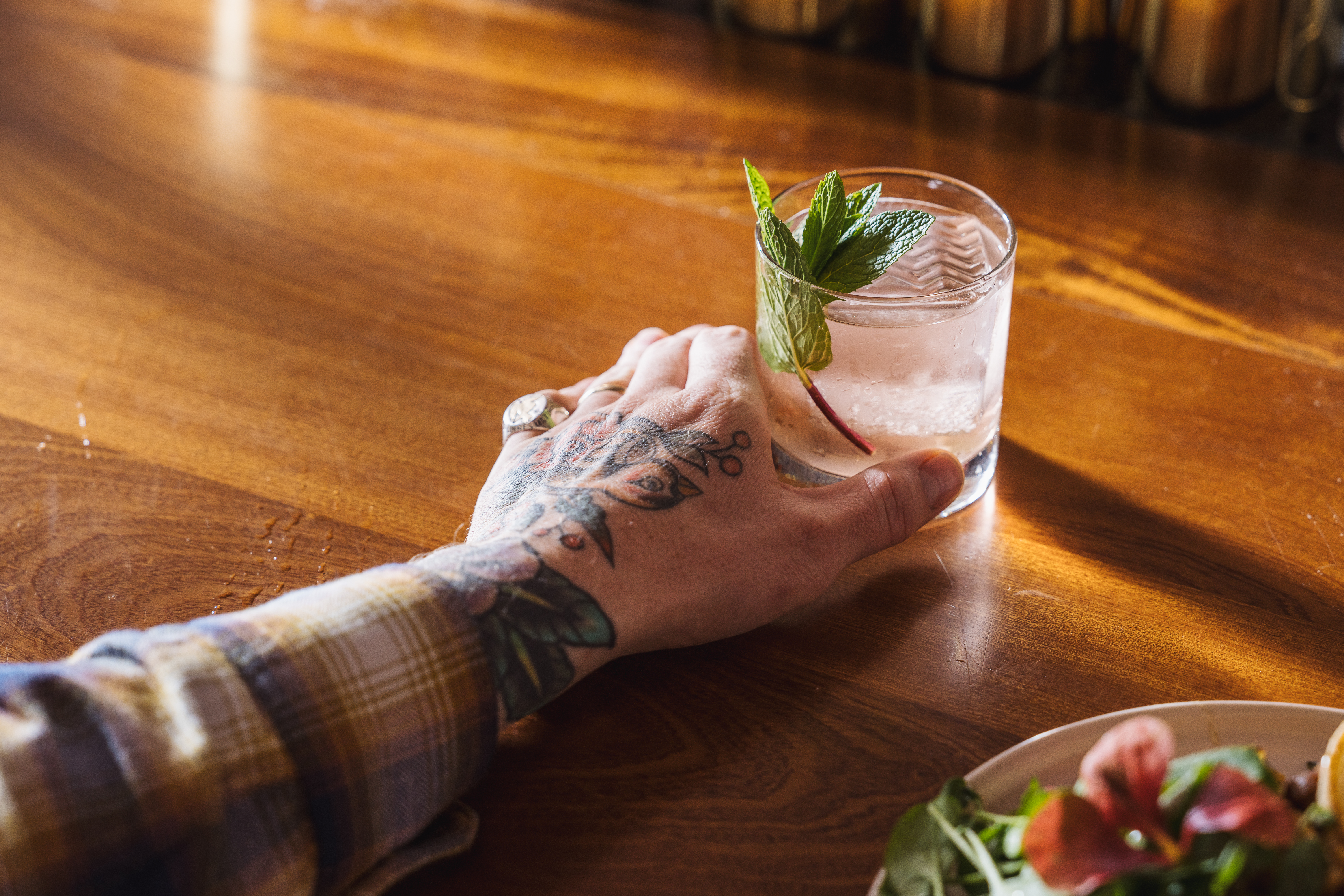 A tattooed arm holds the Guava Wars cocktail at Dirty Pretty.