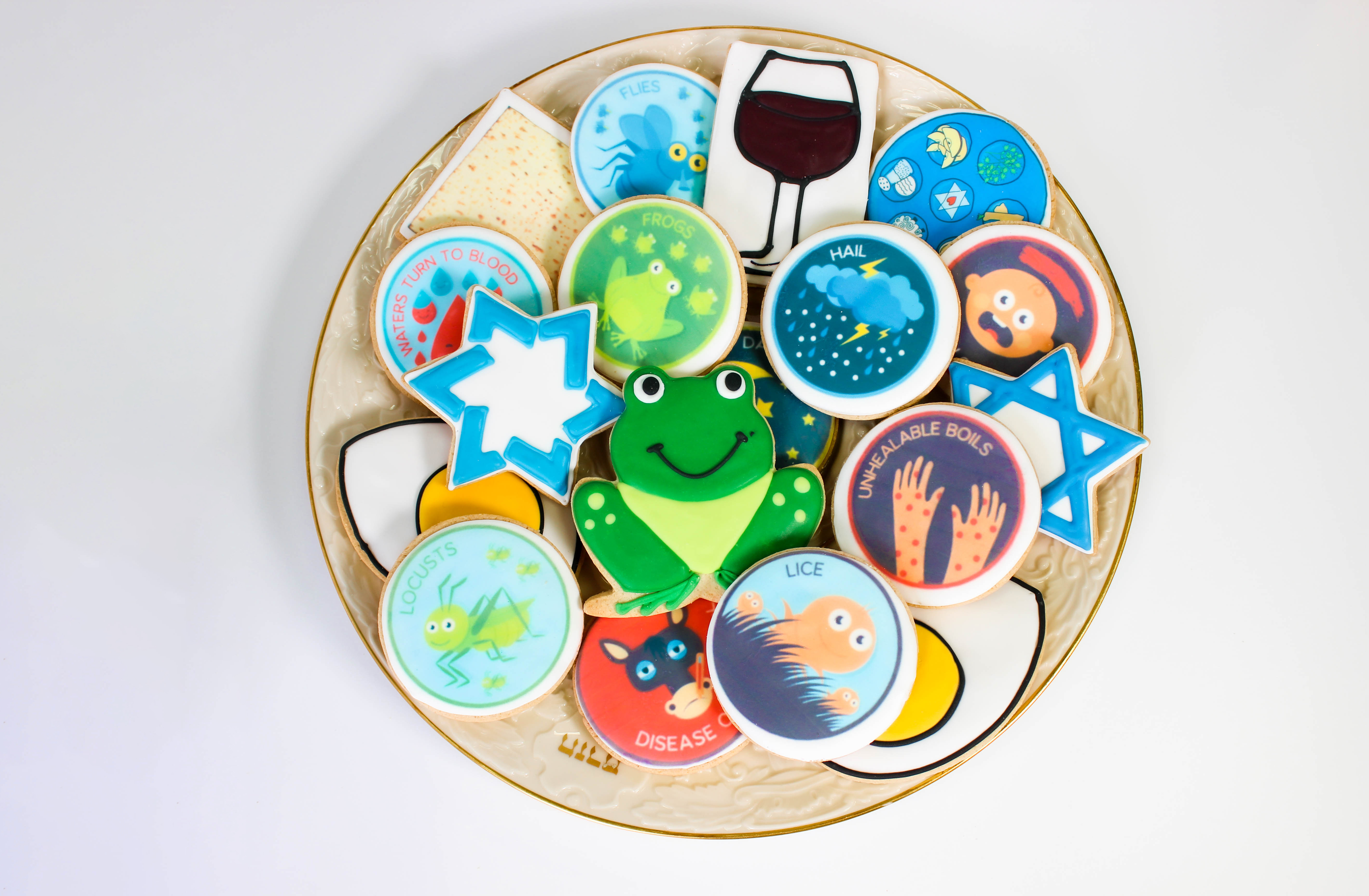 A platter of colorful iced cookies with illustrations of the Plagues of Passover.