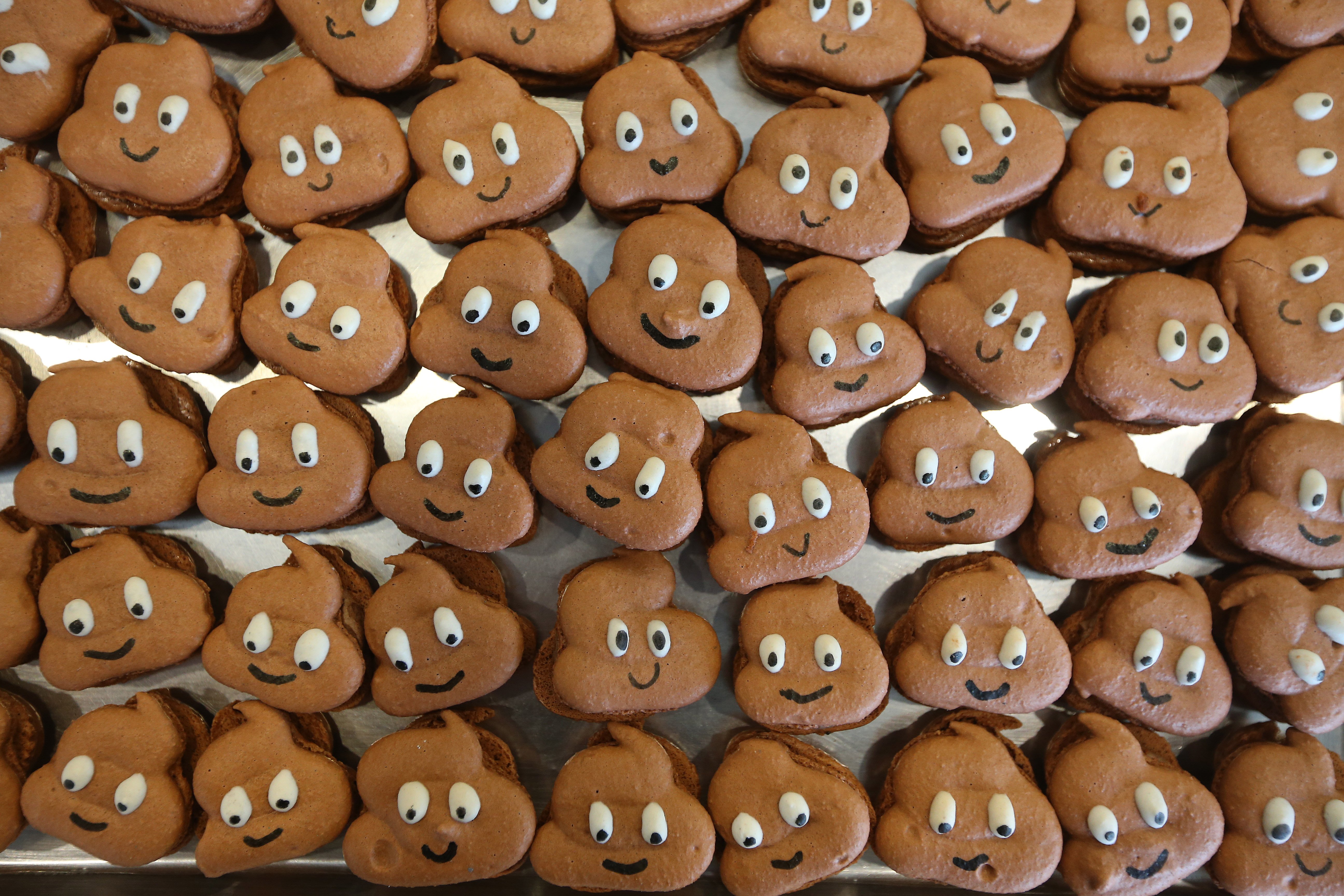 Macarons shaped like the poop emoji with smiley faces on them. 