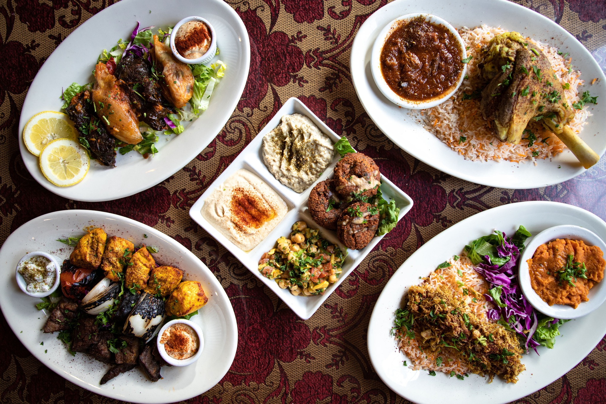 A plate of lamb shank, meze, and other dishes on a table at Dar Salam in Portland, Oregon.