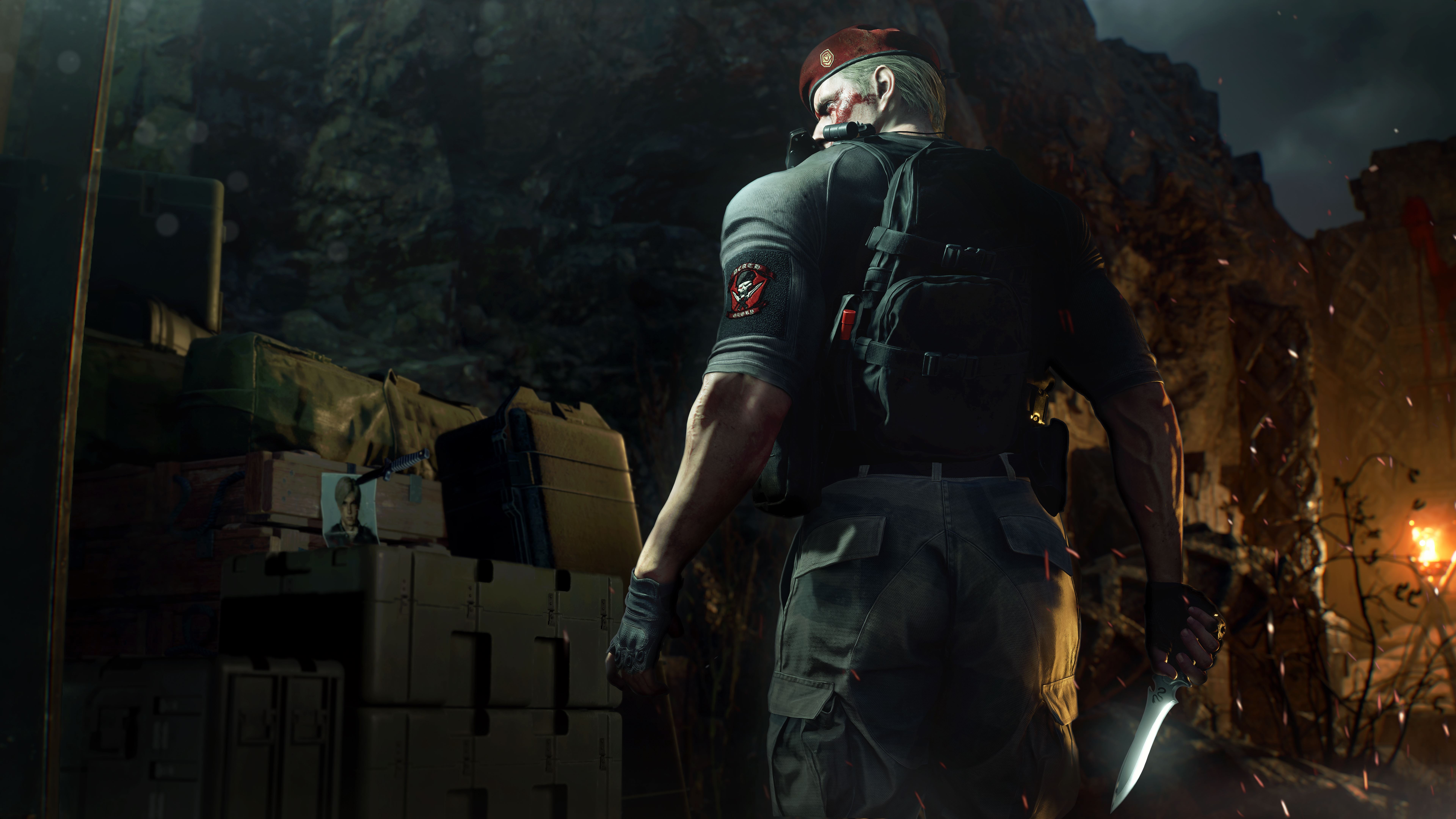 A screenshot of Resident Evil 4 remake focusing on the back of Jack Krauser. In front of him is a stack of crates and a photograph of Leon S. Kennedy — with a knife through his face.