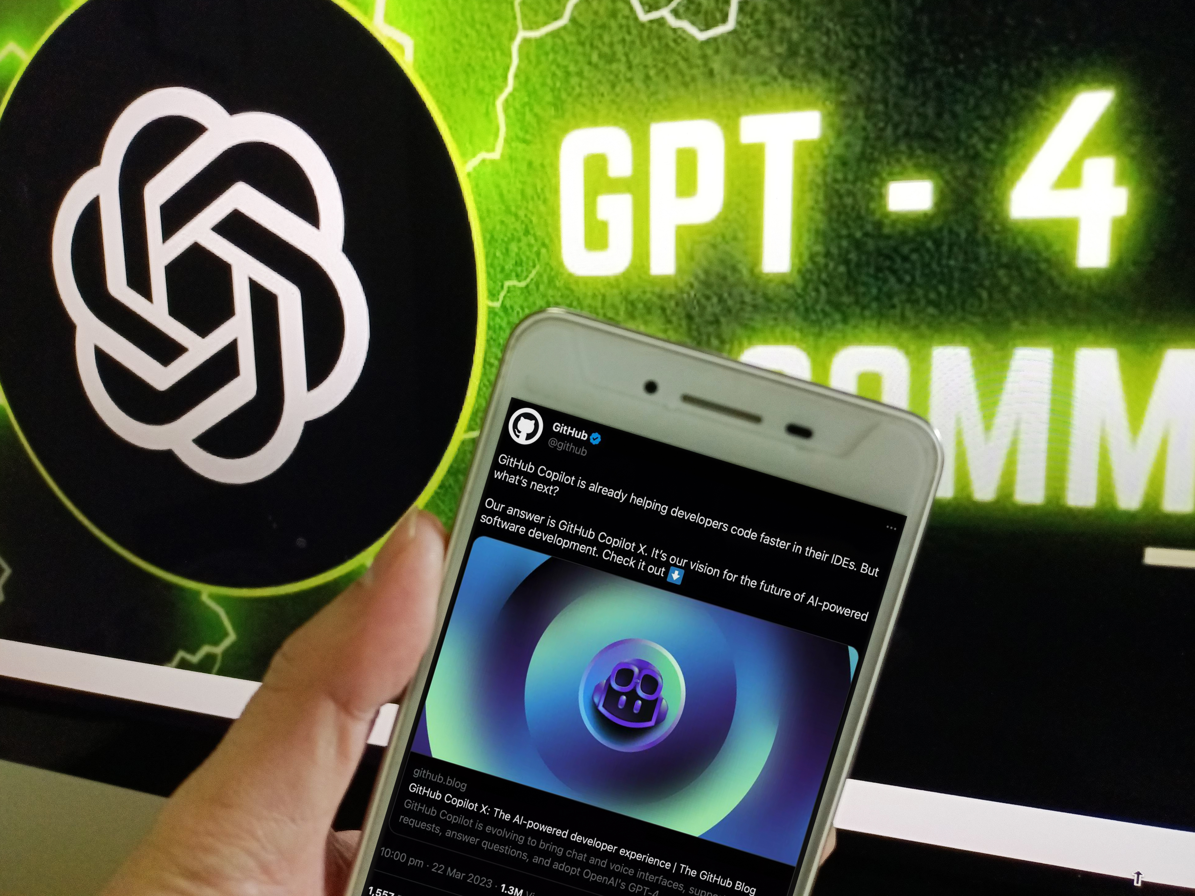 A hand holding a phone in front of a screen with the OpenAI logo and the term GPT-4.
