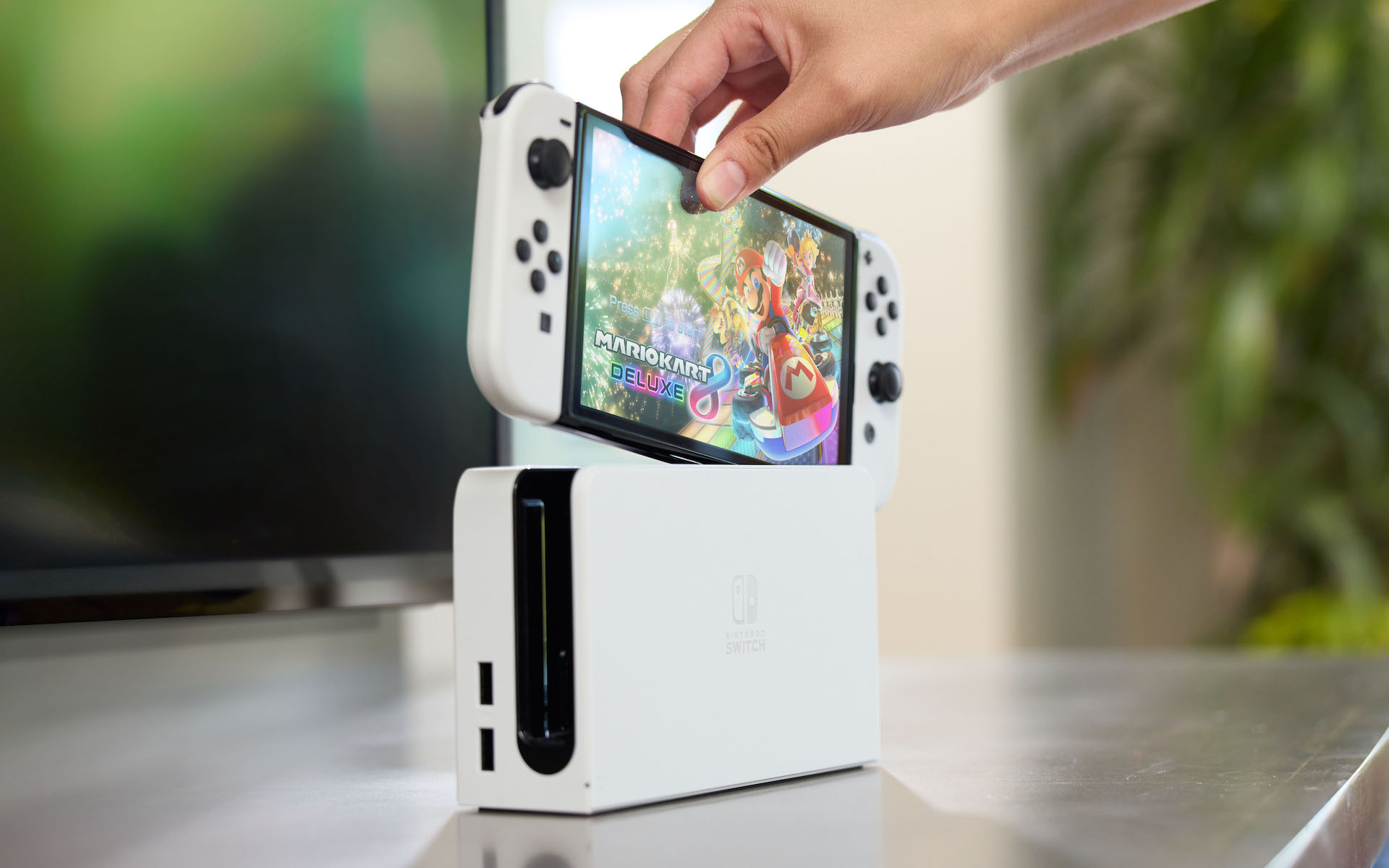 A Nintendo Switch OLED Model being inserted into its dock