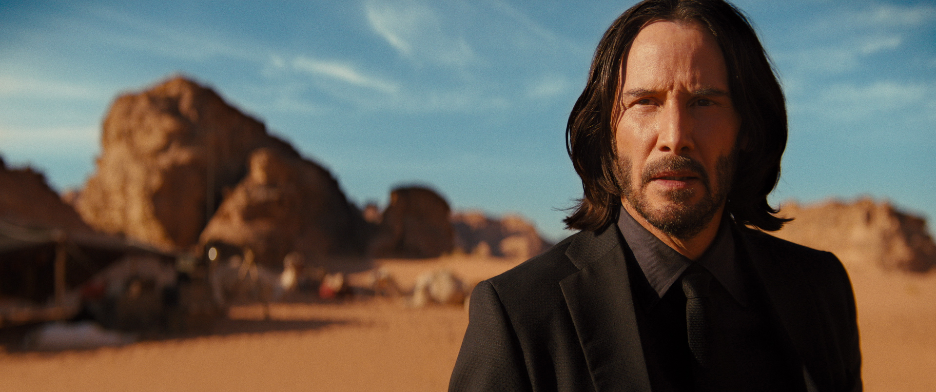John Wick (Keanu Reeves) stands in a desert in Jordan in John Wick: Chapter 4