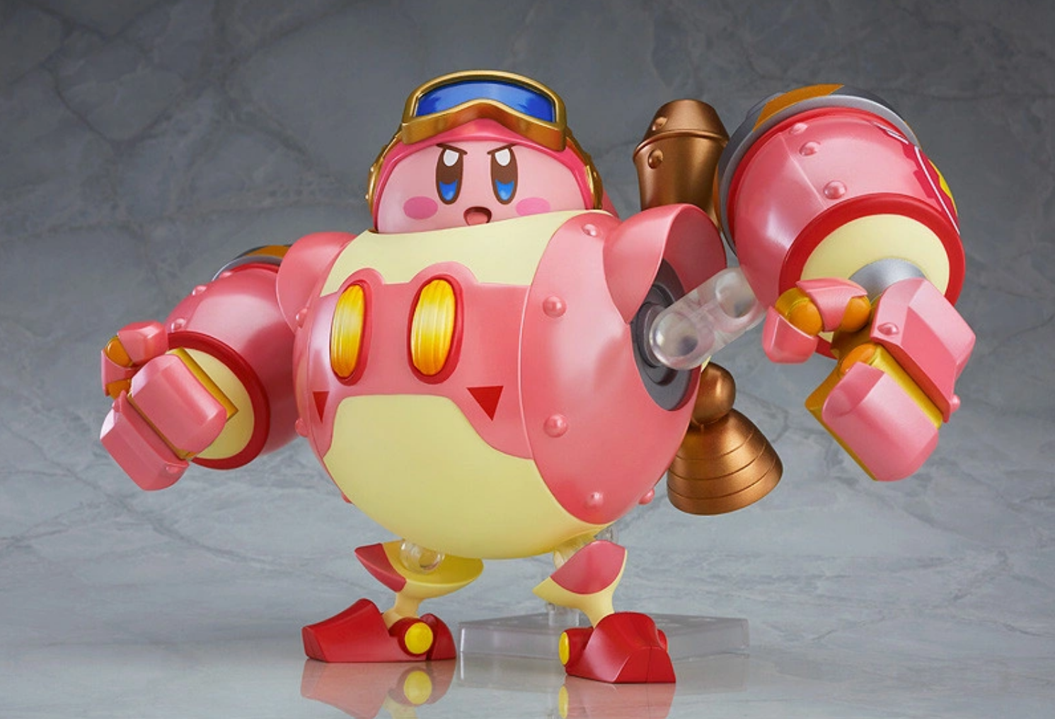 A Kirby figure, which the round pink character in a mech suit. The toy is created by Good Smile Company.