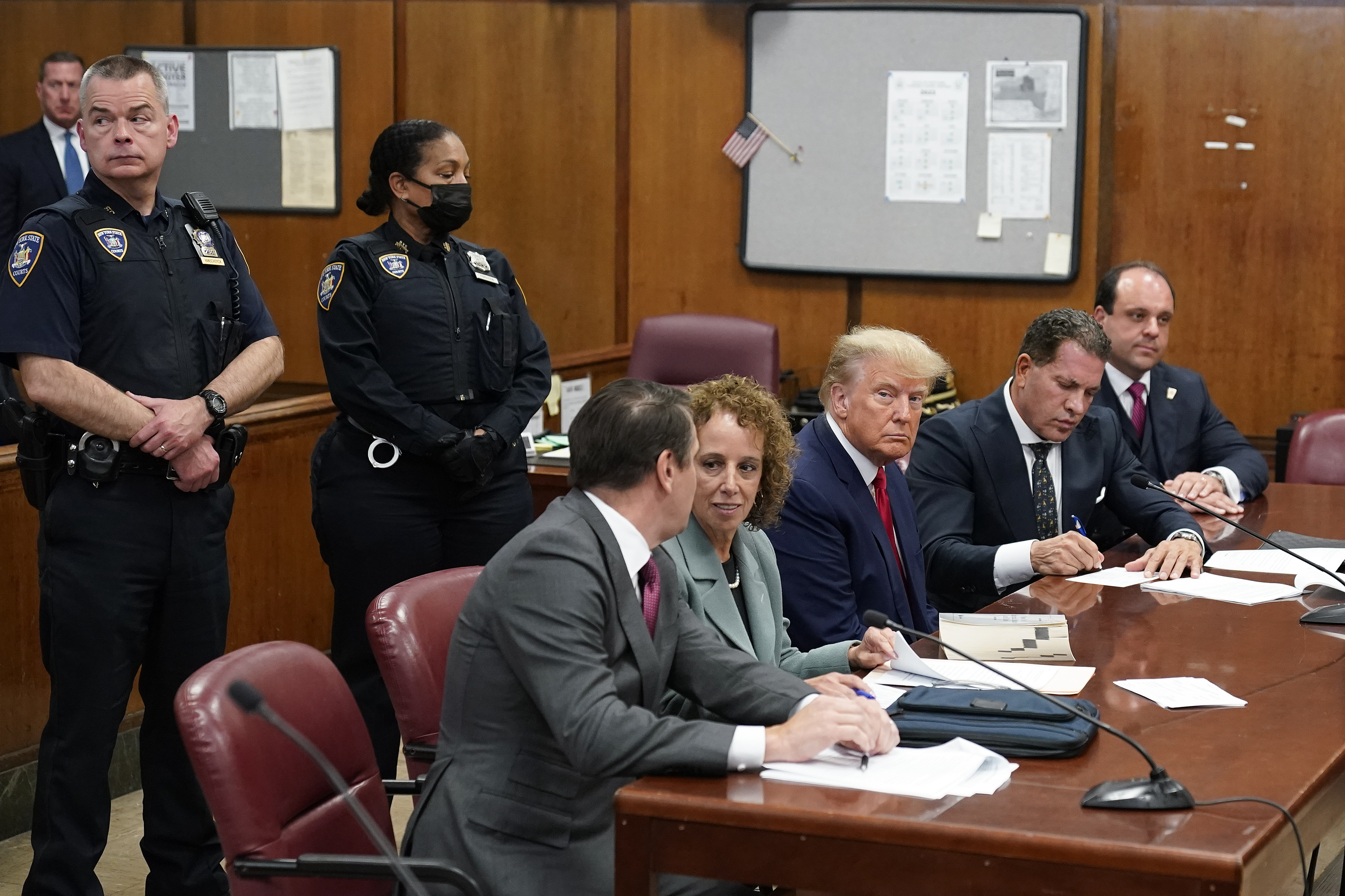 Trump sits in a courtroom flanked by attorneys. 