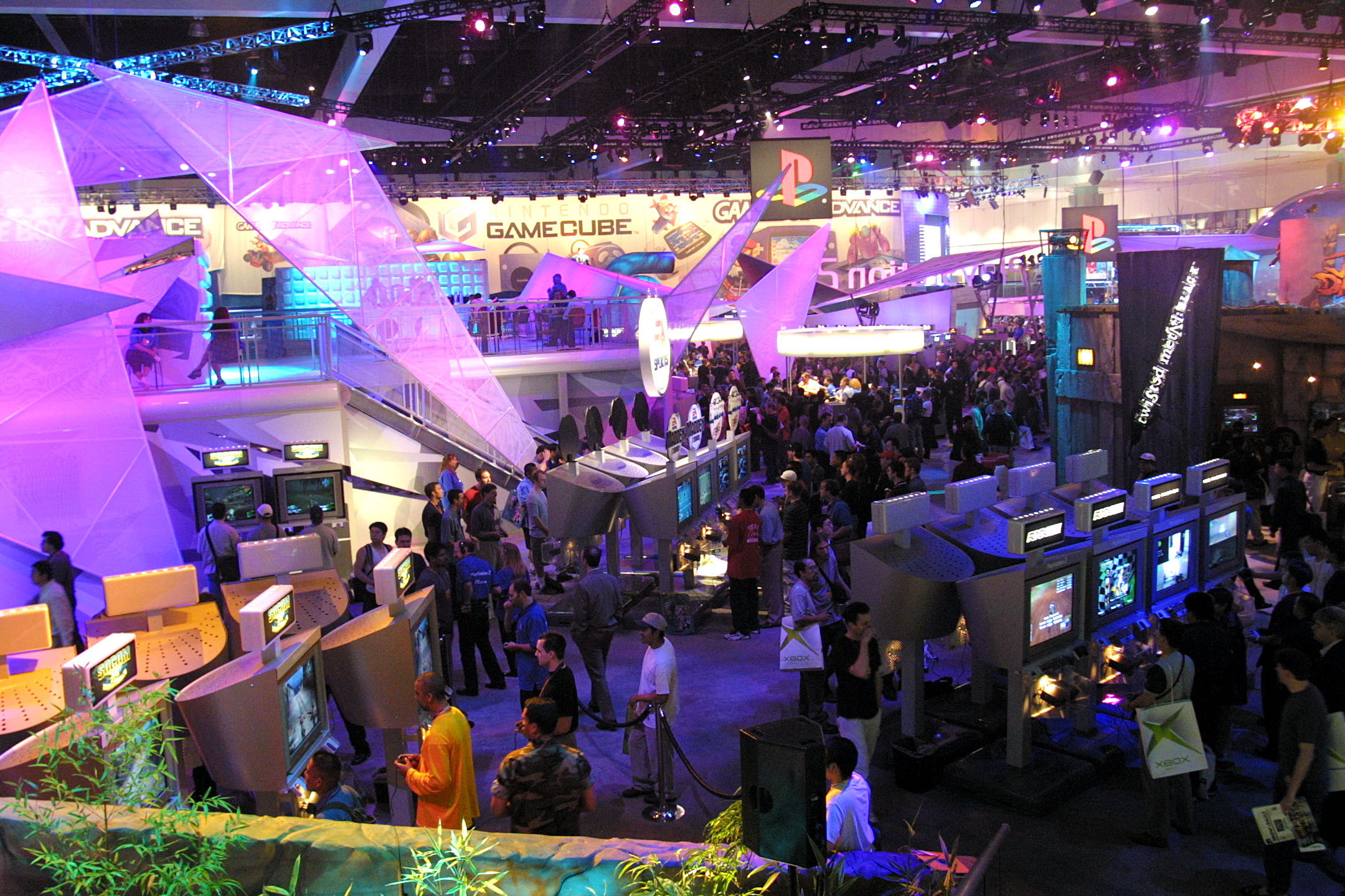 A view of an expo show floor packed with attendees, screens, and brightly colored stands