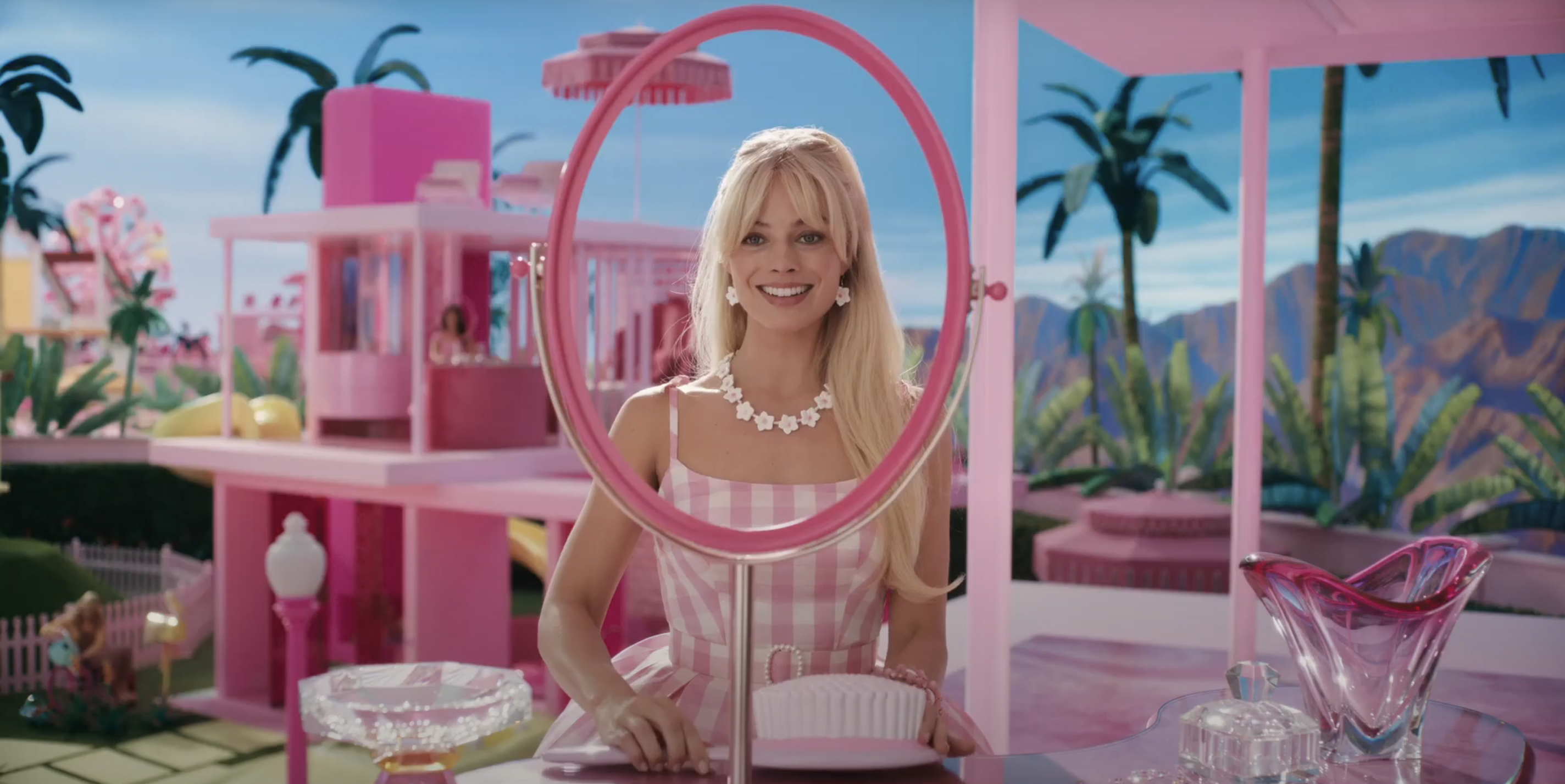 Barbie (Margot Robbie) staring and smiling through a round mirror frame