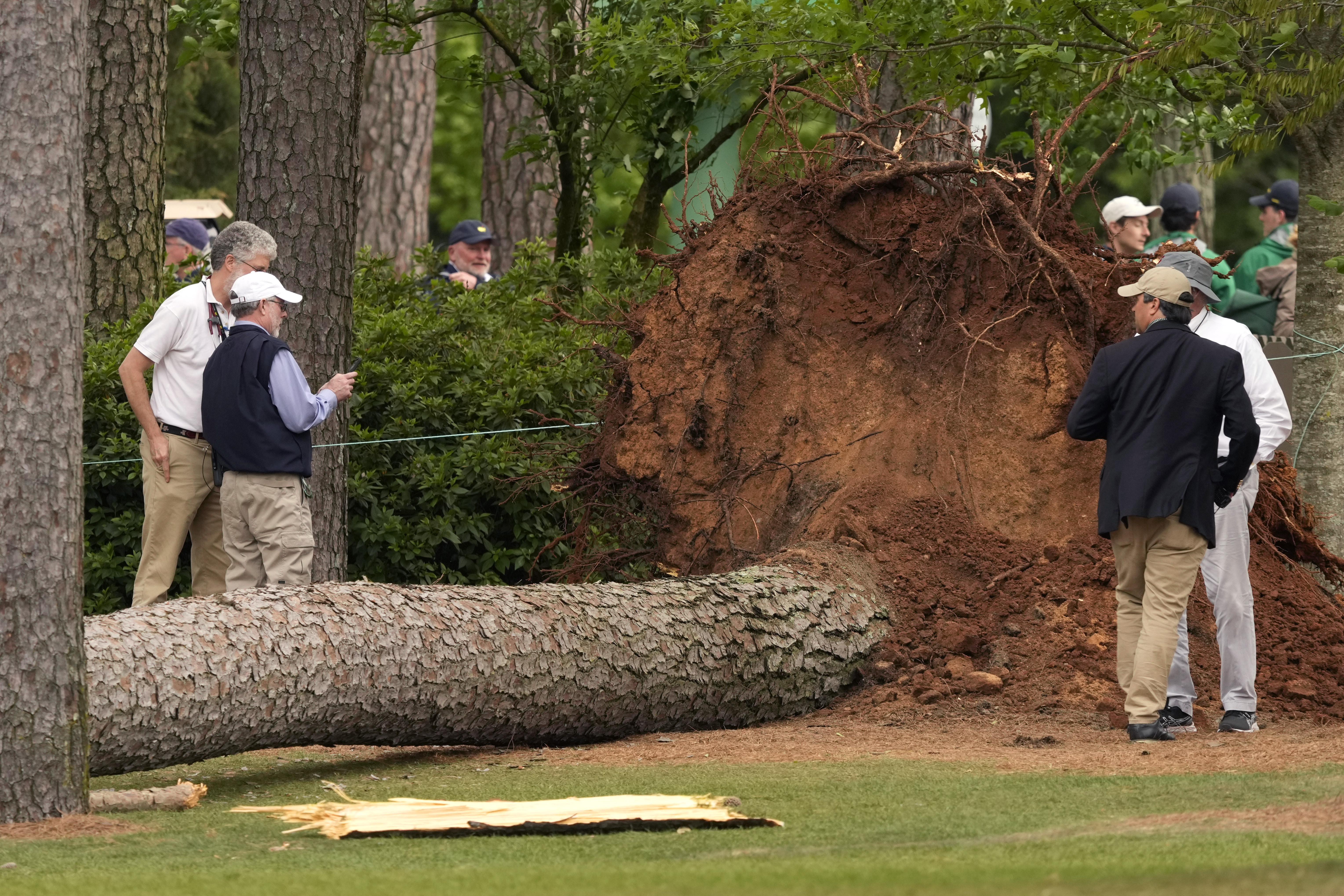 Volunteers and staff secure the area around where a tree fell near the 17th tee during the second round of The Masters golf tournament.