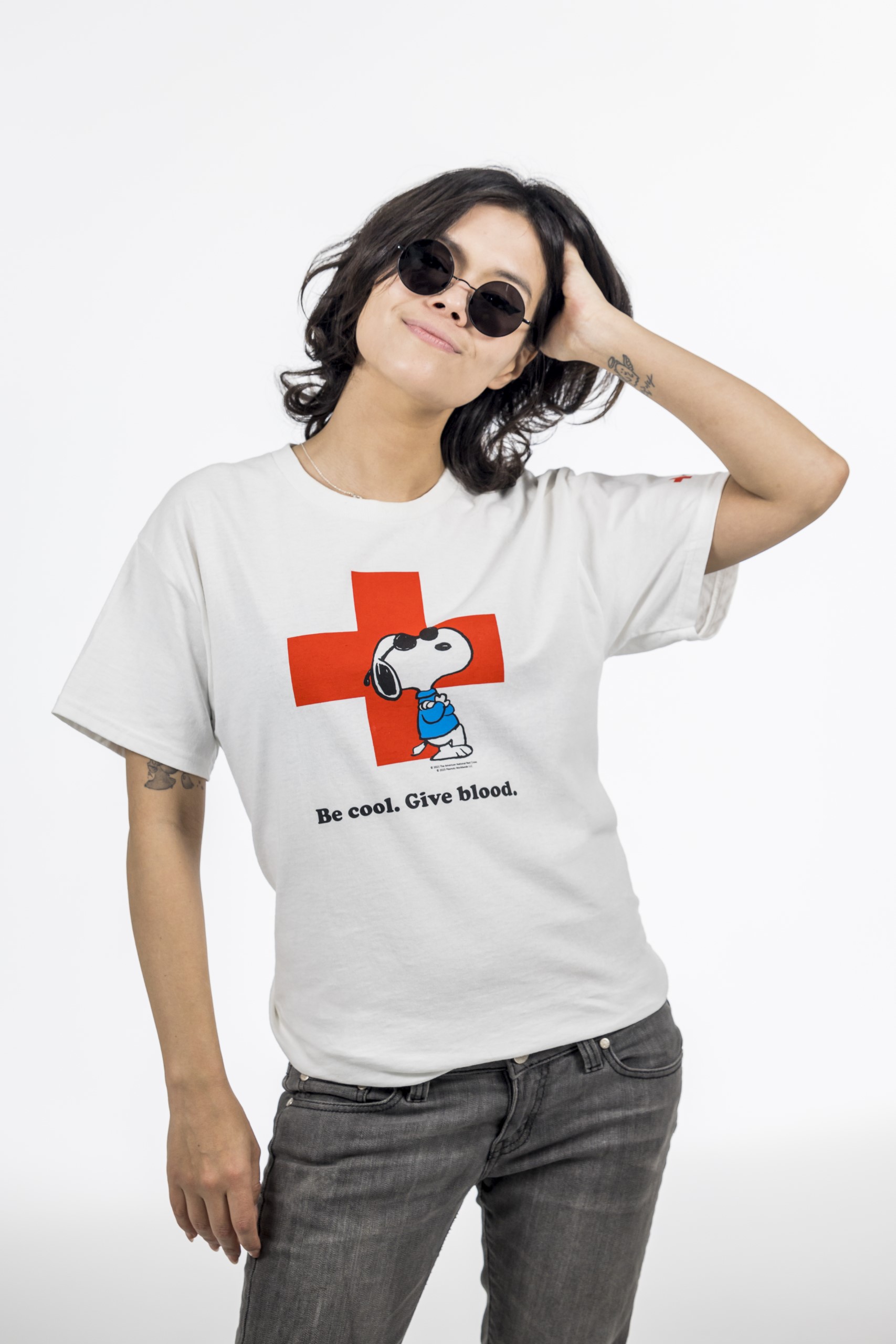 A photo of a person wearing a white t-shirt with Snoopy on it. It has Joe Cool/Snoopy leaning against a the logo of the Red Cross.