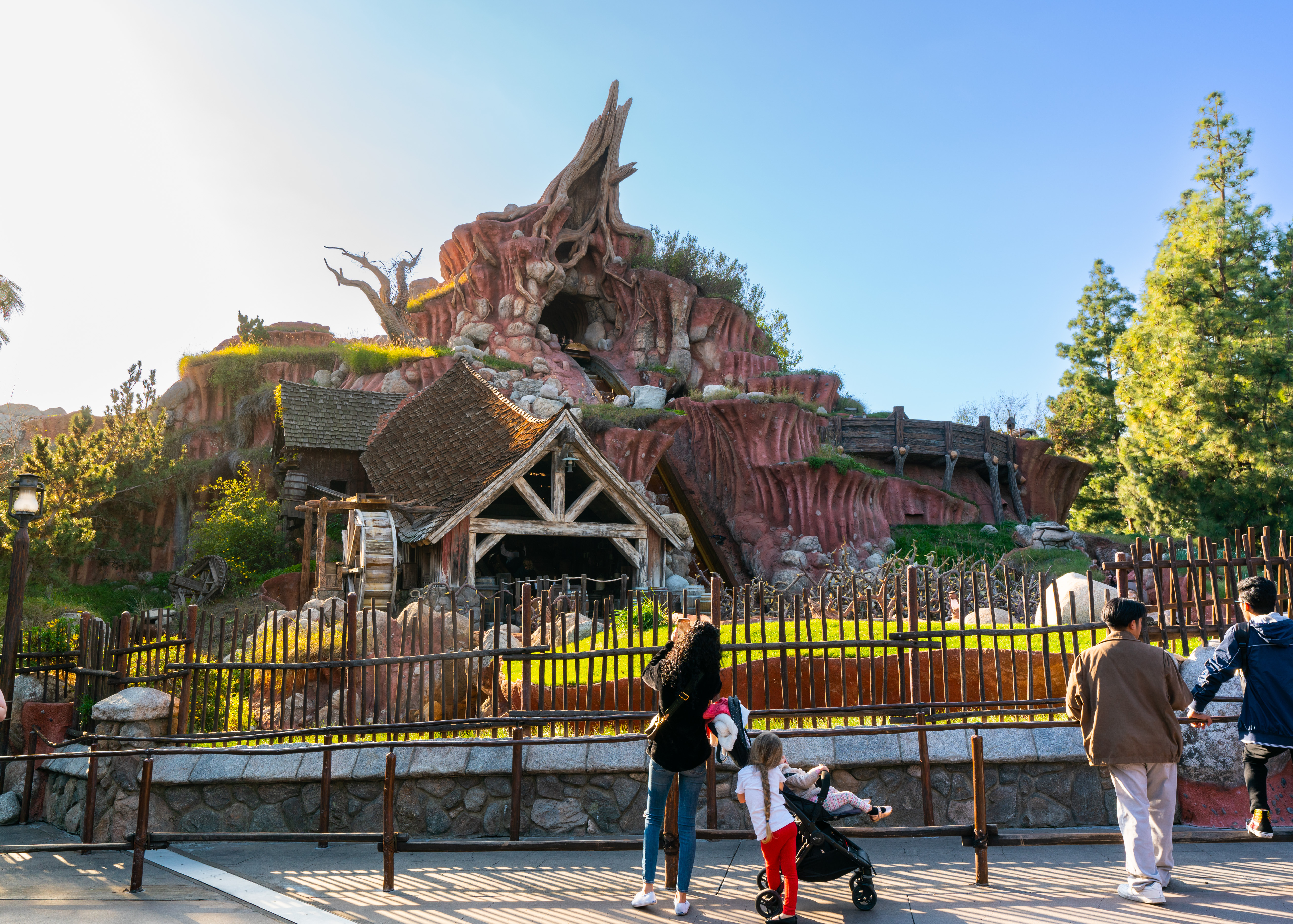 A photo of Splash Mountain at Disneyland, in Anaheim, California. It’s a sunny day and parkgoers are taking a photo of the attraction. 