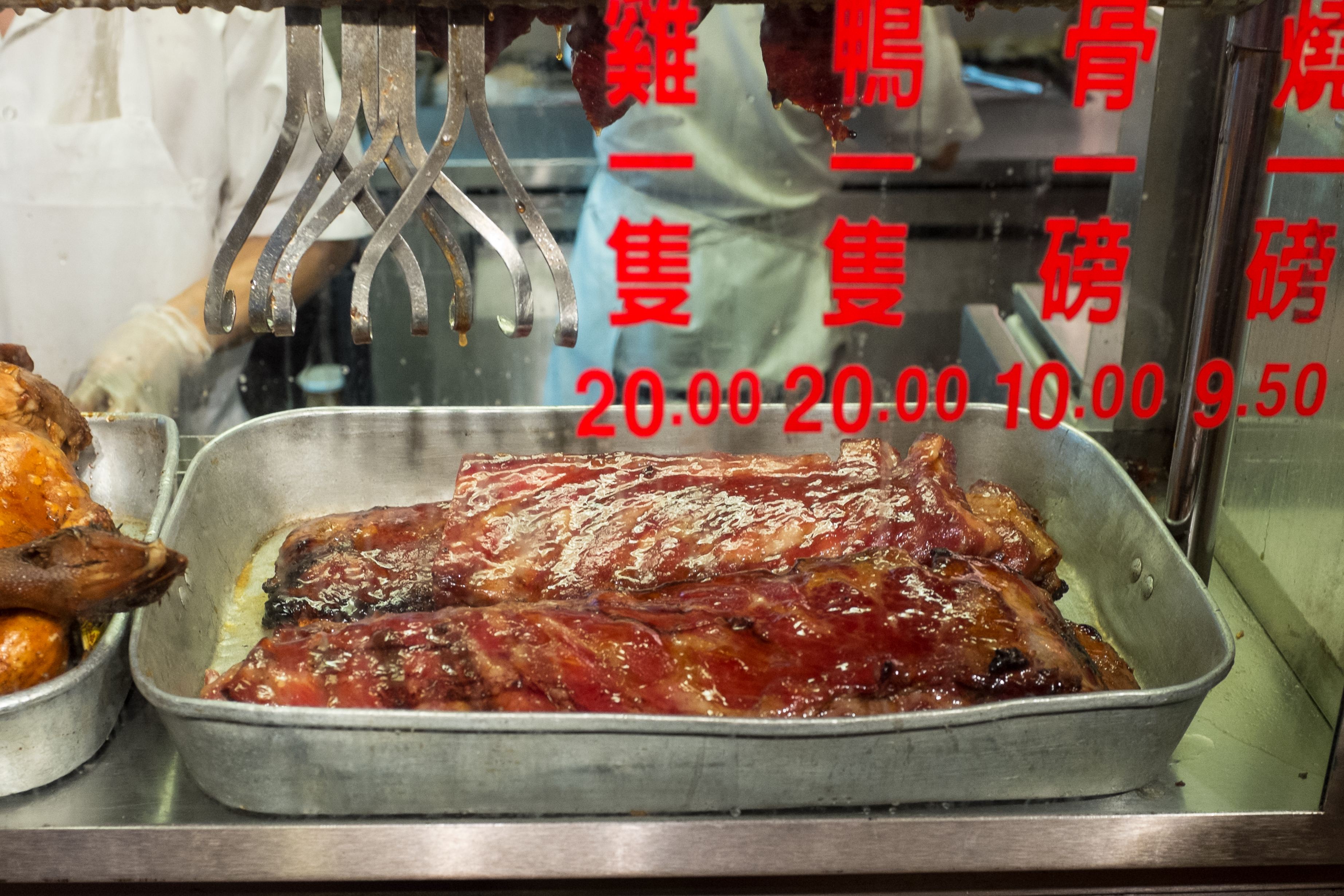 Ribs gleam in the window of a Chinatown restaurant, Big Wong, next to prices marked on the window in rent letters.