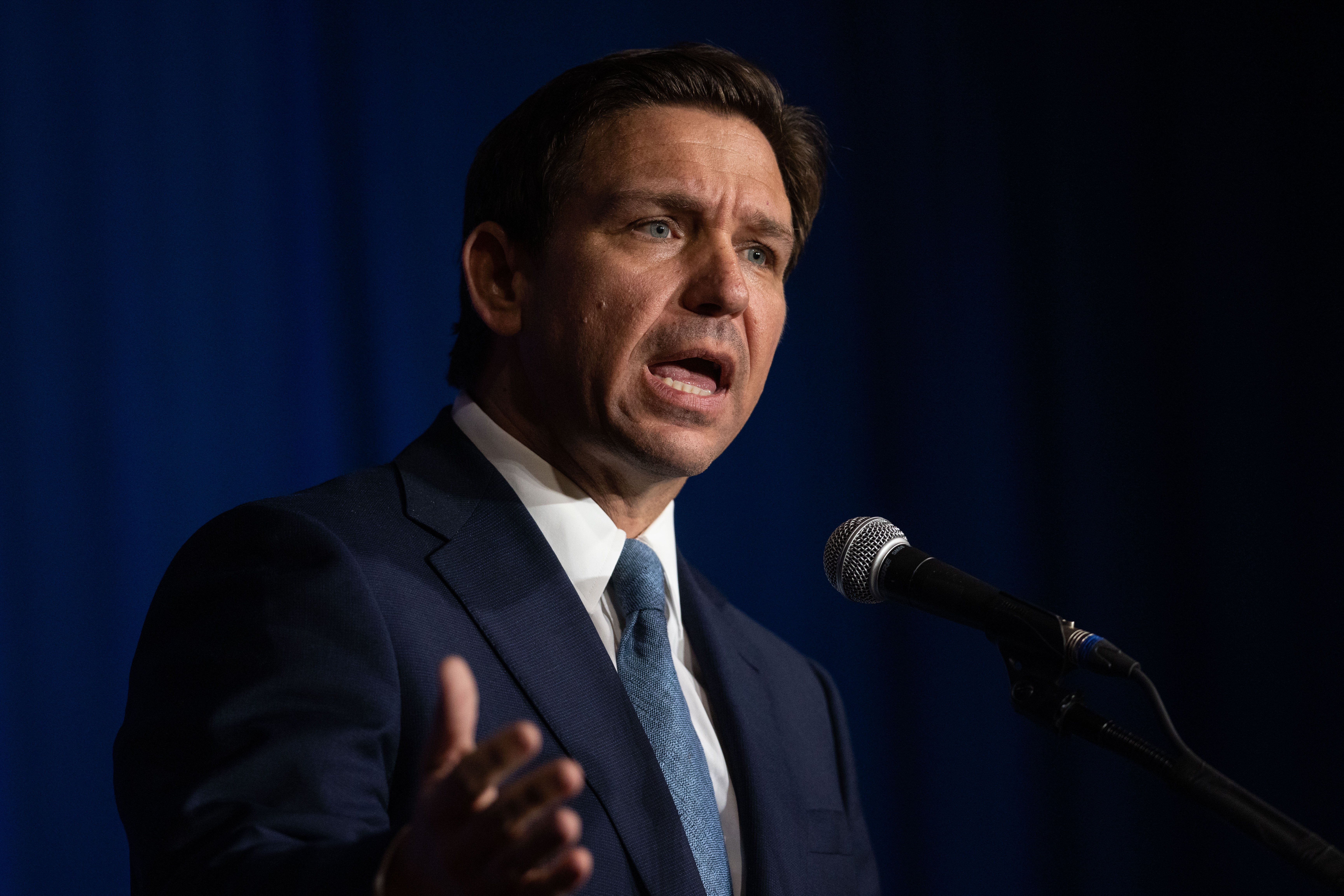 Ron DeSantis speaks in front of a microphone.