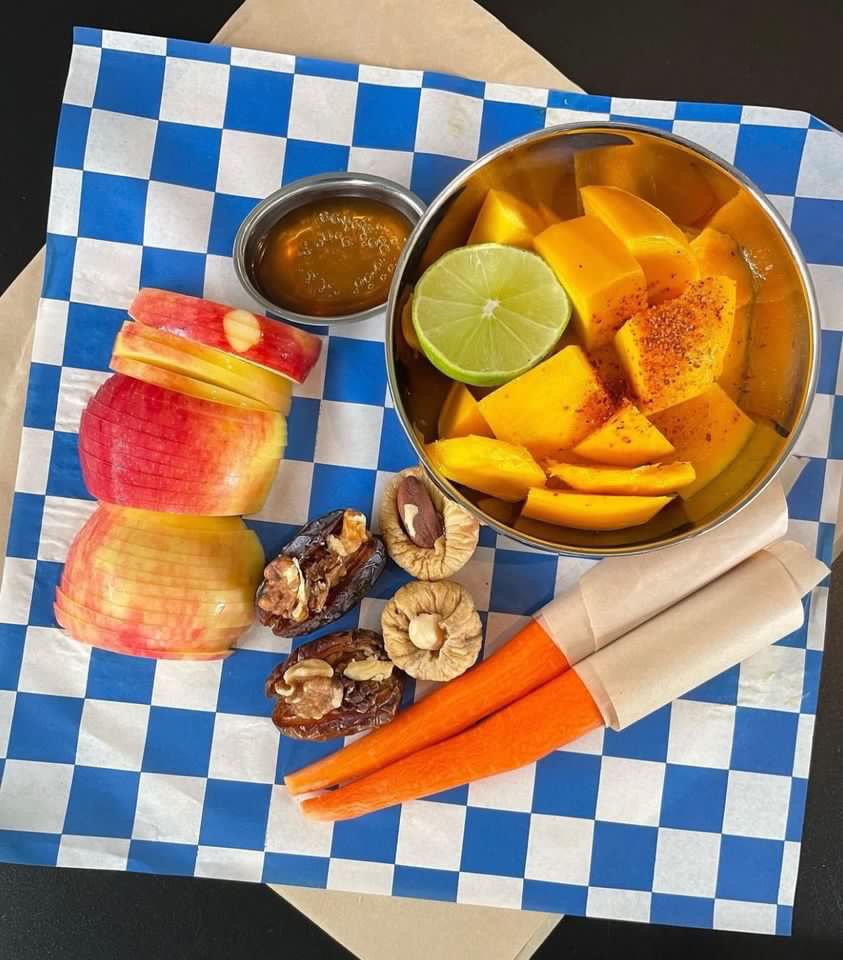 Some fruit with chili powder, sliced apples, figs with walnut, and two carrots from Cafe Prince in Core City, Detroit, Michigan.