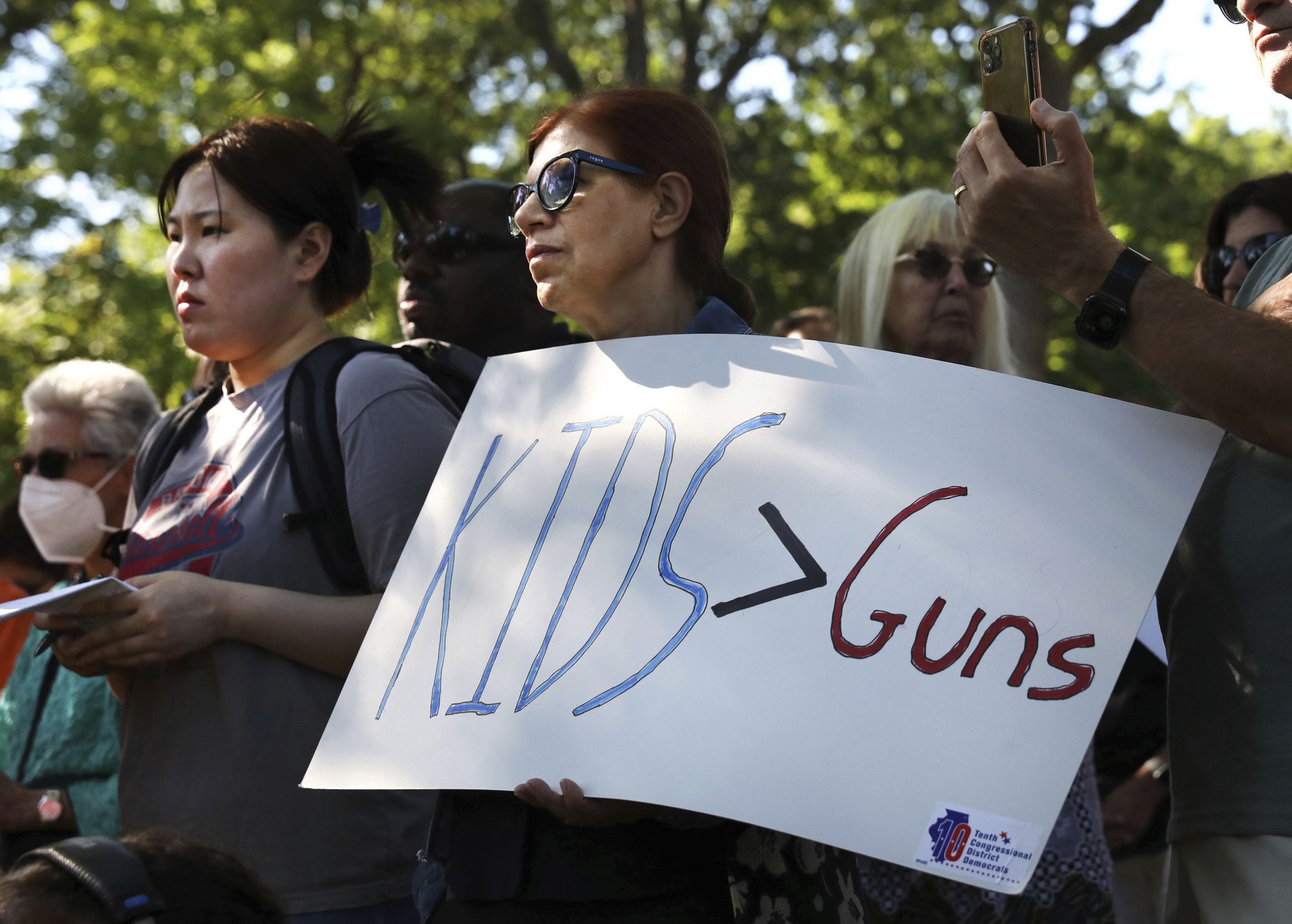 Mourners hold a sign that says Kids &gt; Guns. 
