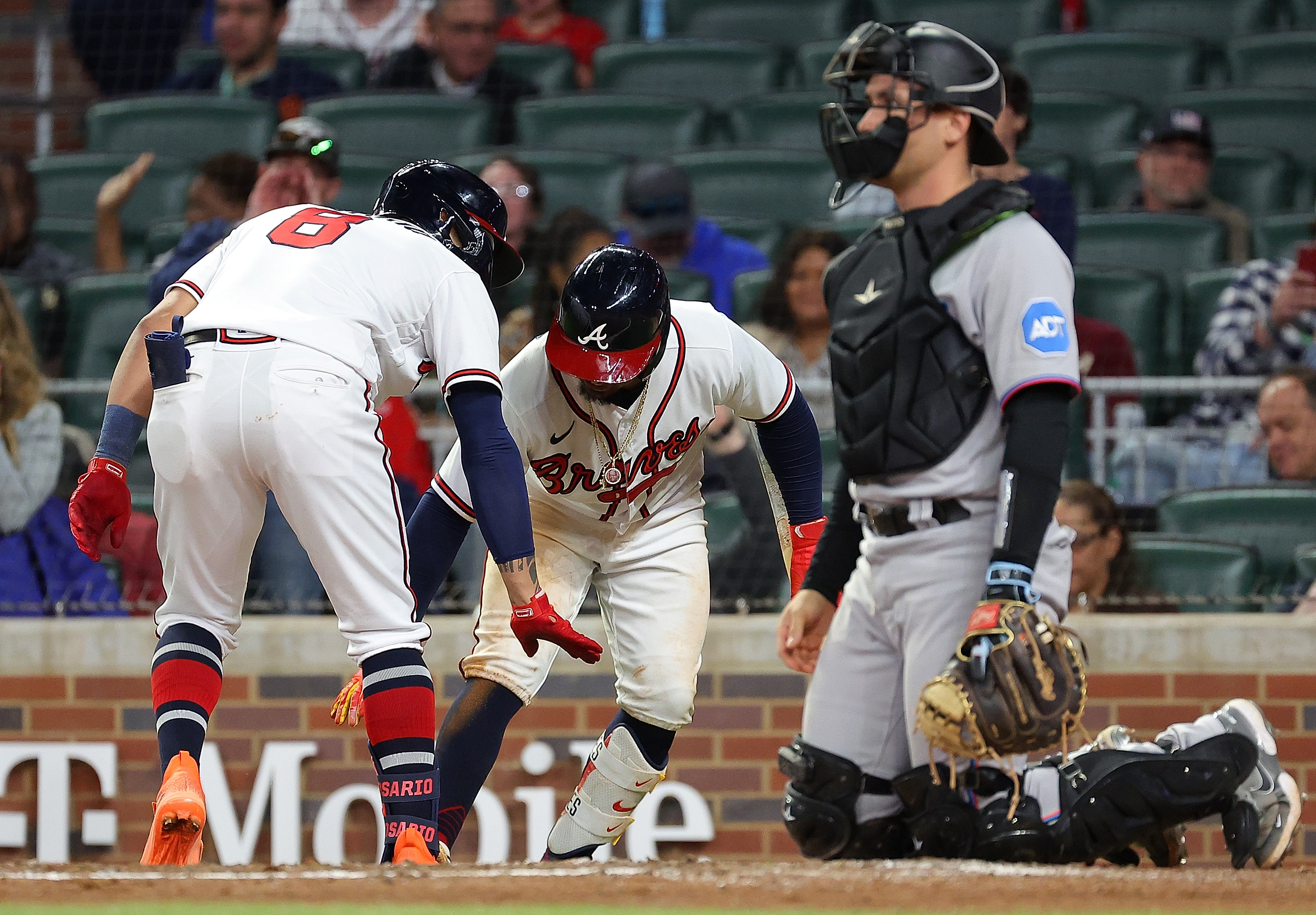 Eddie Rosario #8 of the Atlanta Braves reacts with Ozzie Albies #1 after hitting a solo homer in the eighth inning against the Miami Marlins at Truist Park on April 25, 2023 in Atlanta, Georgia.  